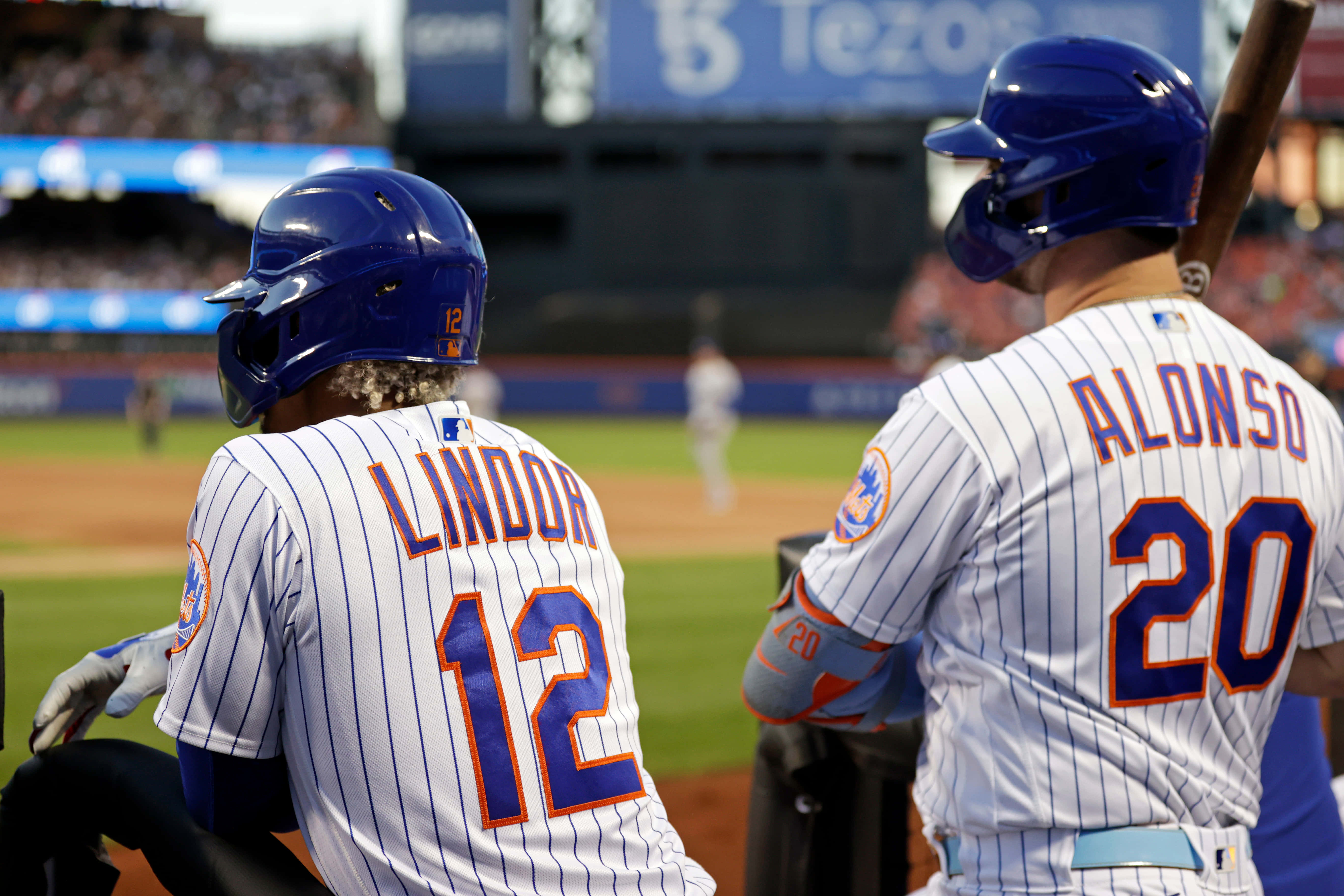 Pete Alonso 桌布 壁紙 — 兩名紐約大都會棒球球員身穿細條紋制服，在日間比賽期間坐在球員休息區。