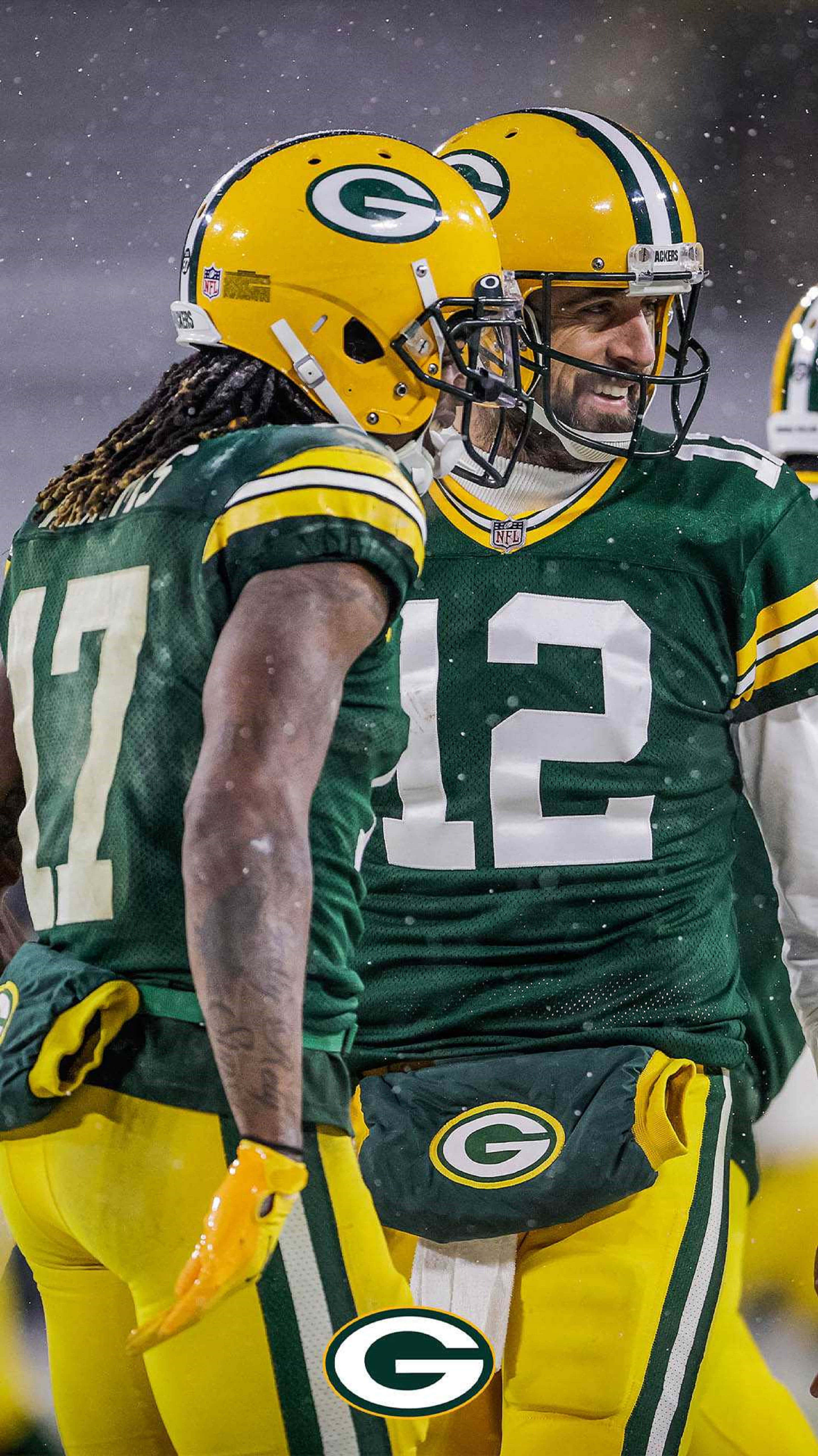 Aaron Rodgers 桌布 壁紙 — 兩名綠灣包裝工美式足球員身穿綠色和金色球衣，在球場燈光下的雪地中擁抱。