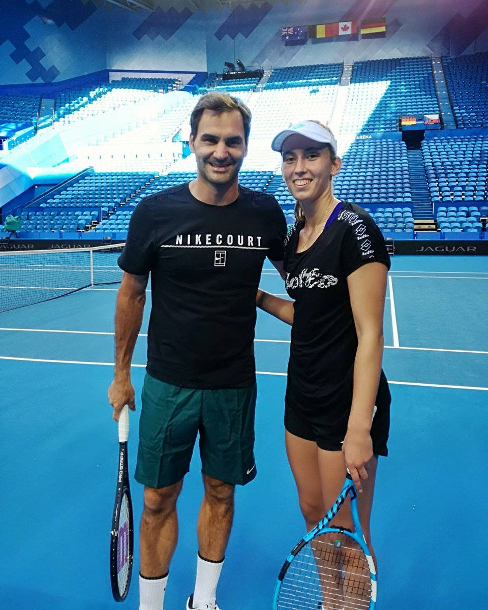 Tennis 桌布 壁紙 — 兩名網球運動員在充滿活力的藍色硬地球場上微笑拍照，身後是空蕩蕩的體育場座位。