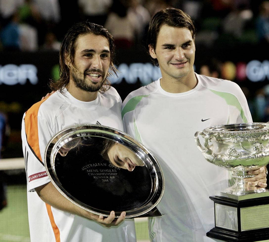 Tennis 桌布 壁紙 — 兩名網球運動員在燈光球場上微笑舉起獎盃，身後有模糊的觀眾。