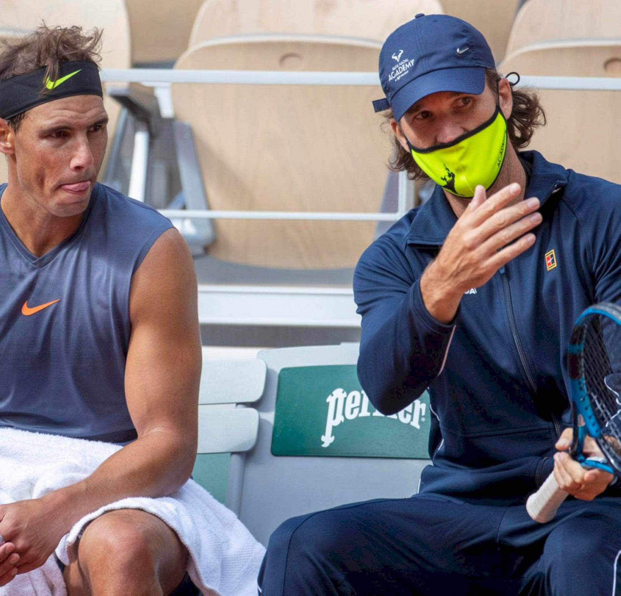 Tennis 桌布 壁紙 — 兩名網球運動員坐在球場長椅上，一人戴著亮黃色口罩做手勢，另一人專注地看著。