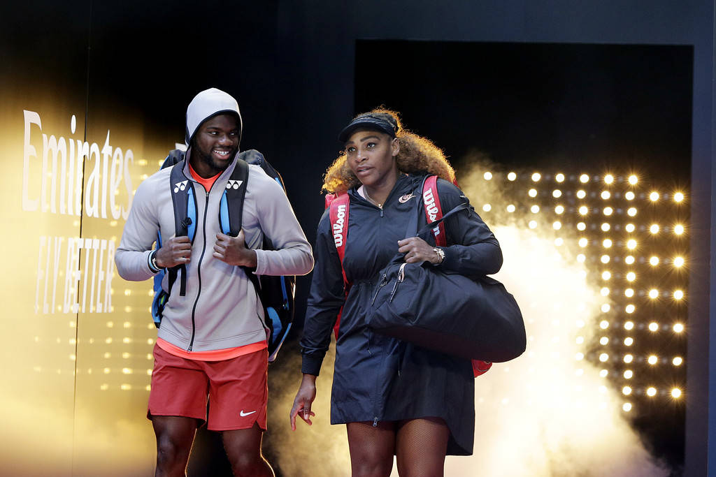 Tennis 桌布 壁紙 — 兩名網球選手自信地走過煙霧瀰漫的場館，場館內有發光的燈光和Emirates品牌背景。
