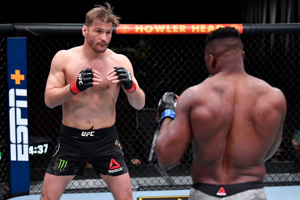 UFC 桌布 壁紙 — 兩名肌肉發達的MMA拳手在帶有ESPN品牌標誌和顯示4:37的數位計時器的八角籠中對峙。