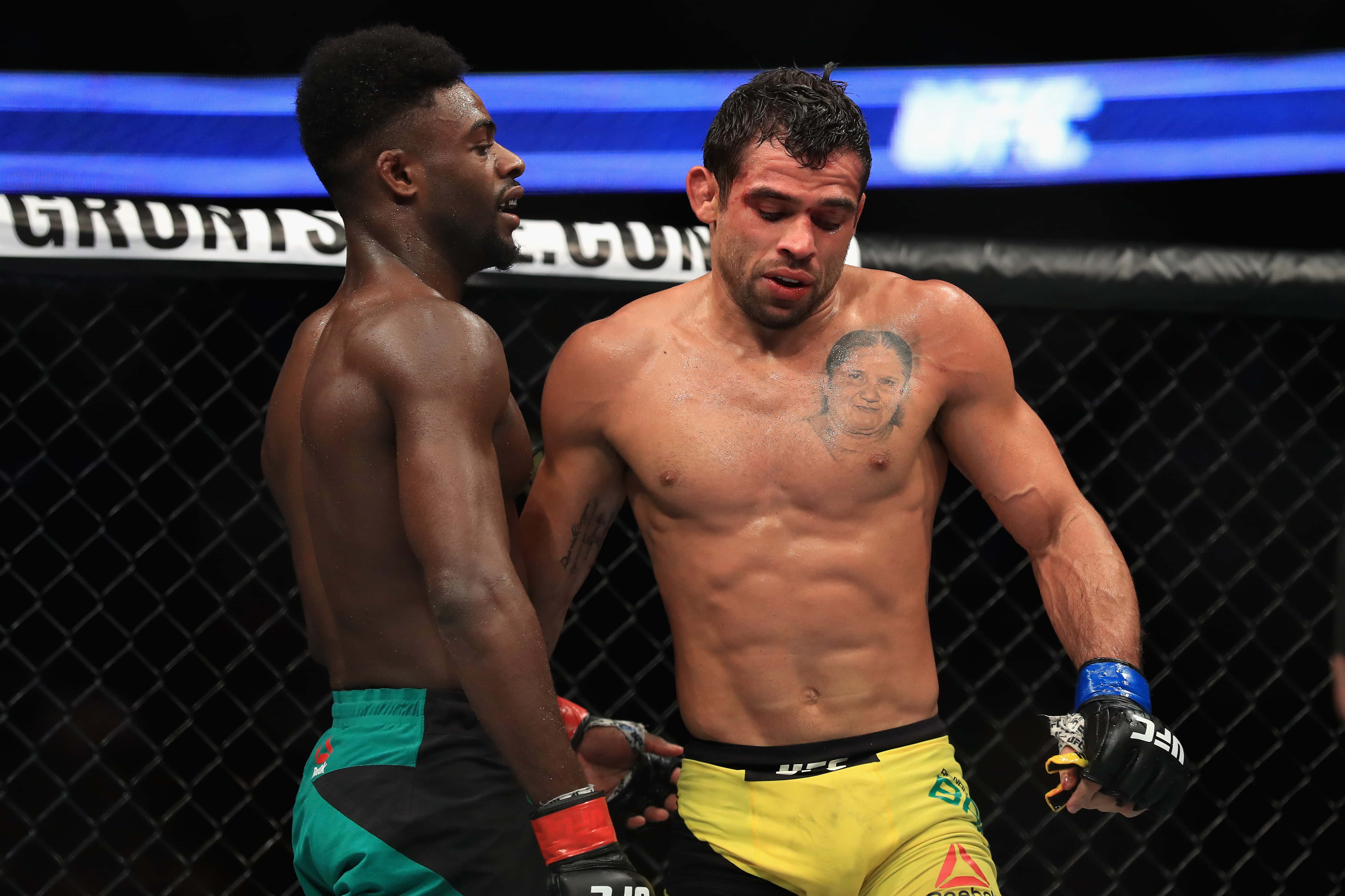 UFC 桌布 壁紙 — 兩名肌肉發達的MMA拳手在明亮的場館燈光下於UFC八角籠中對峙。