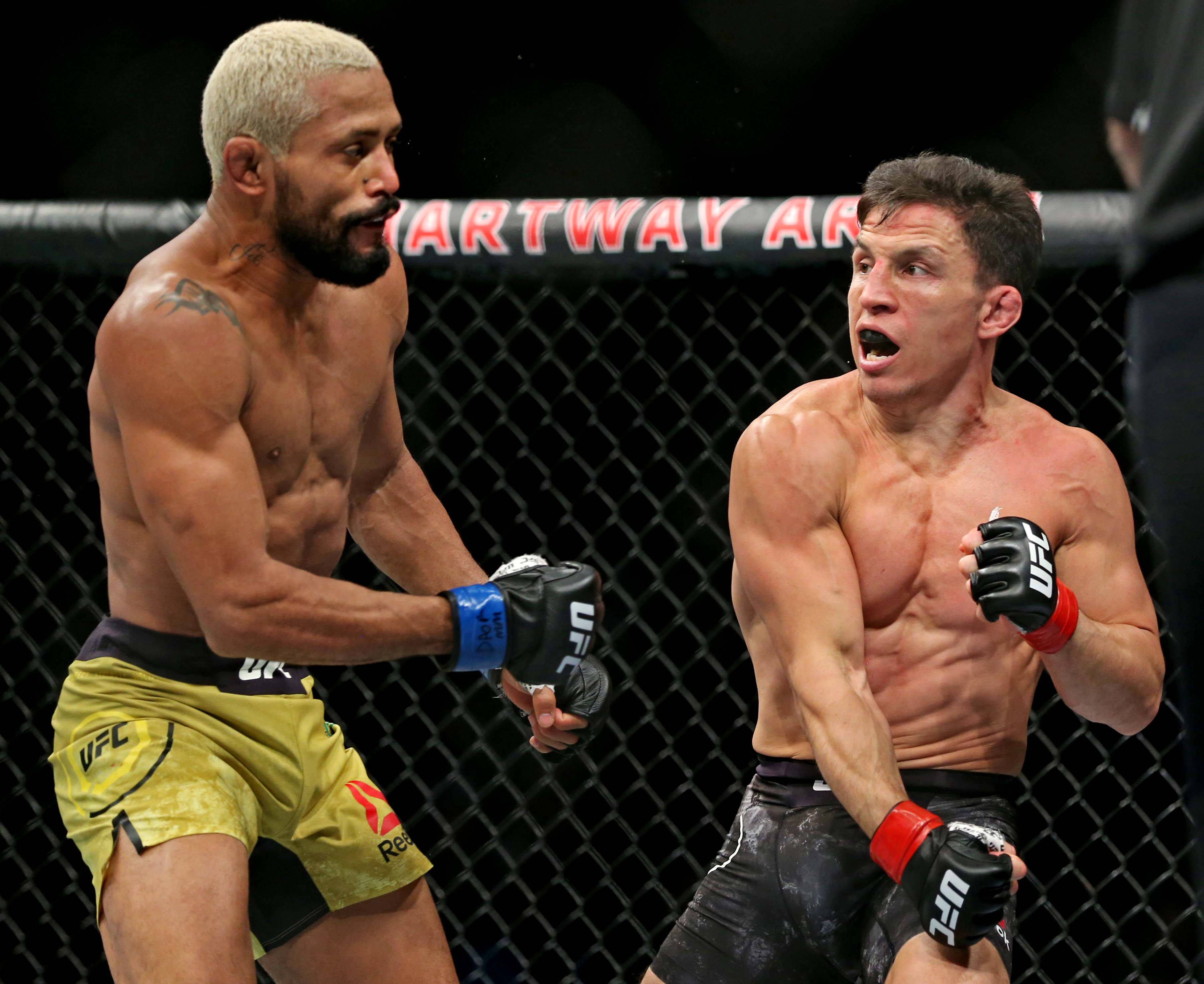 MMA 桌布 壁紙 — 兩名肌肉發達的MMA拳手在明亮的場館燈光下，於UFC八角籠內激烈交鋒。