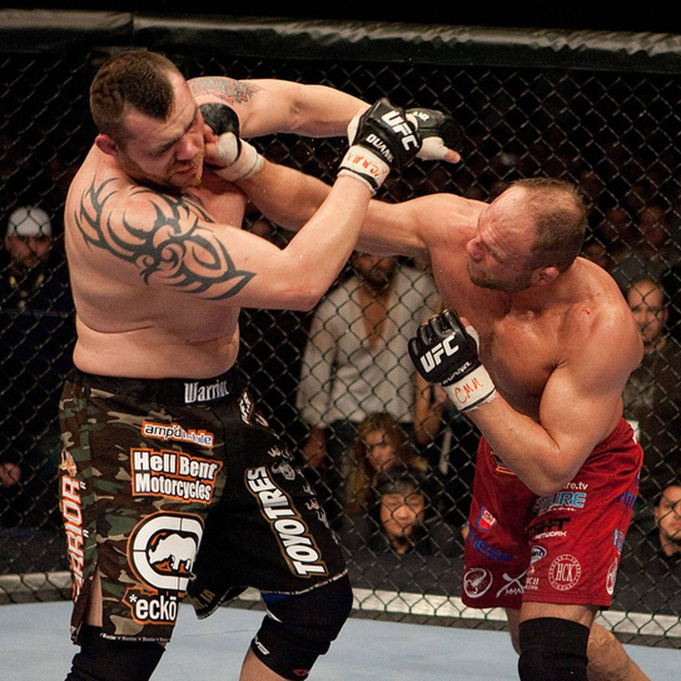 MMA 桌布 壁紙 — 兩名肌肉發達的MMA拳手在明亮的場館燈光下於八角籠內激烈纏鬥。