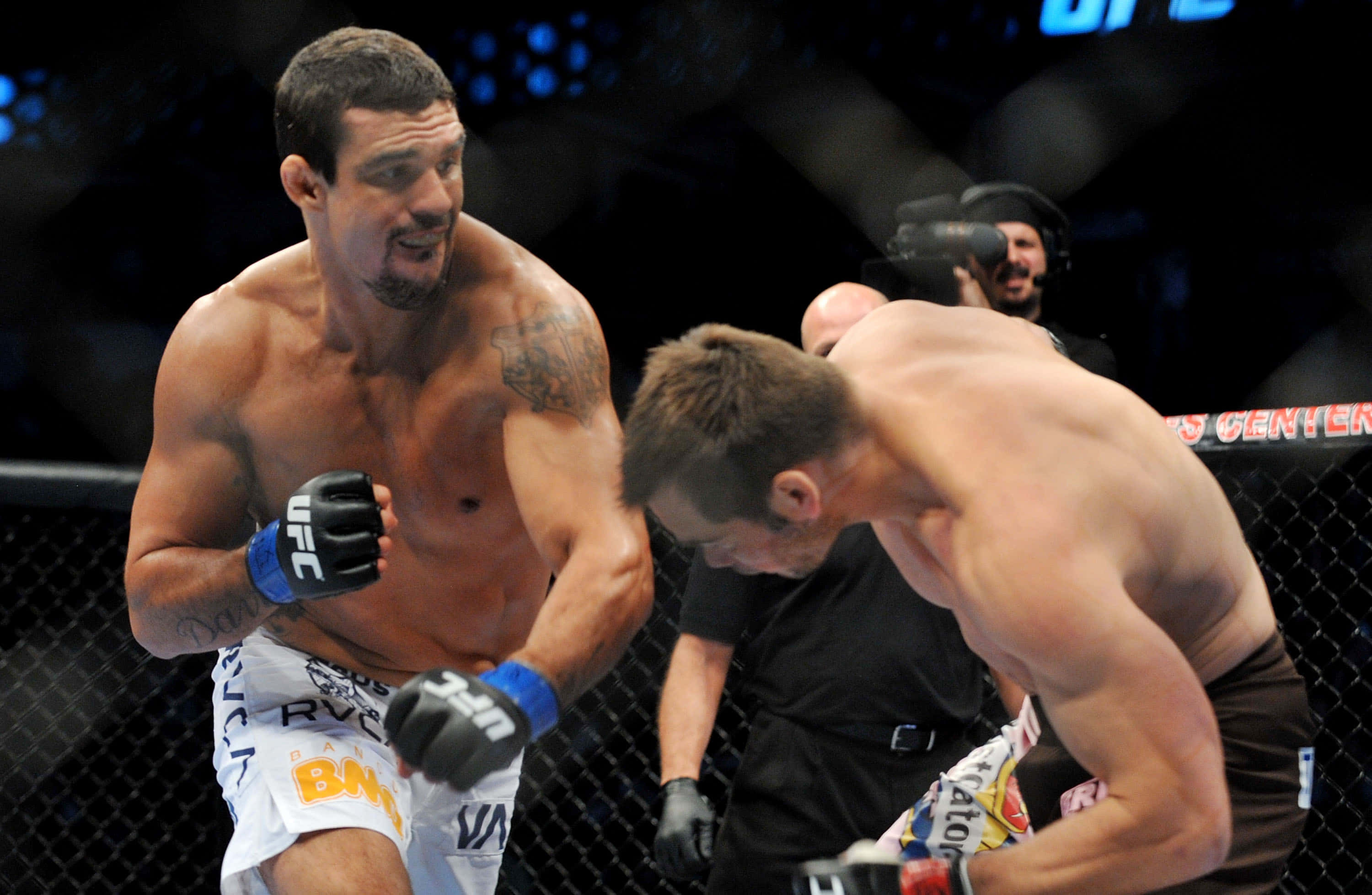 UFC 桌布 壁紙 — 兩名肌肉發達的MMA拳手在明亮的場館燈光下於UFC八角籠內激烈交鋒。