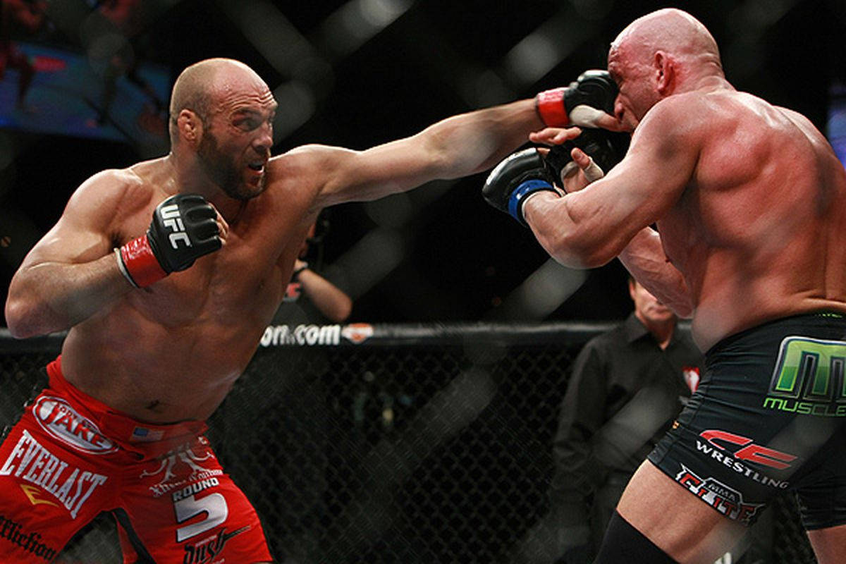 MMA 桌布 壁紙 — 兩名肌肉發達的MMA拳手在激烈的鐵籠賽中交鋒，其中一人打出強力一拳。