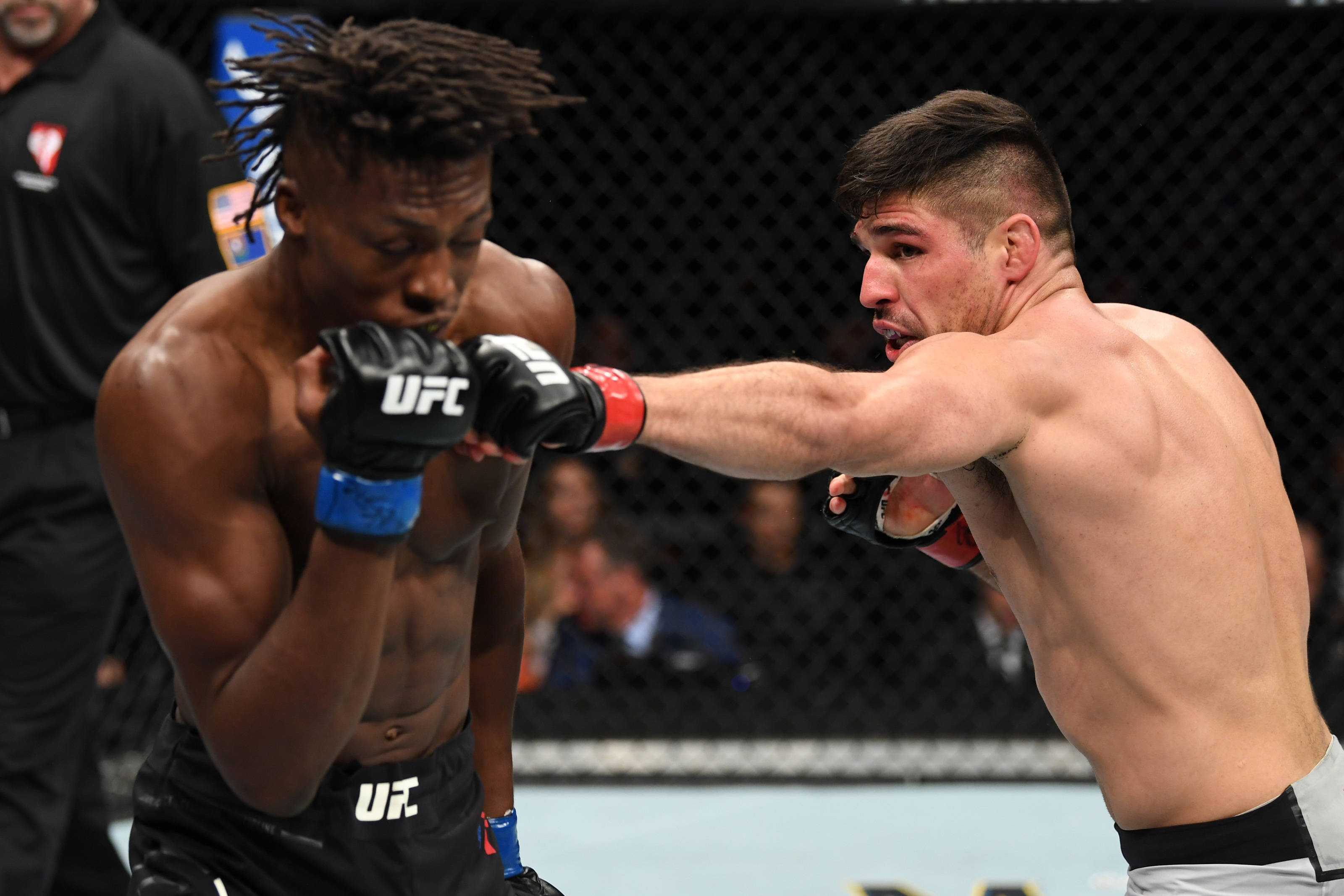 MMA 桌布 壁紙 — 兩名肌肉發達的MMA拳手在激烈的鐵籠賽中交鋒，其中一人打出強力一拳。