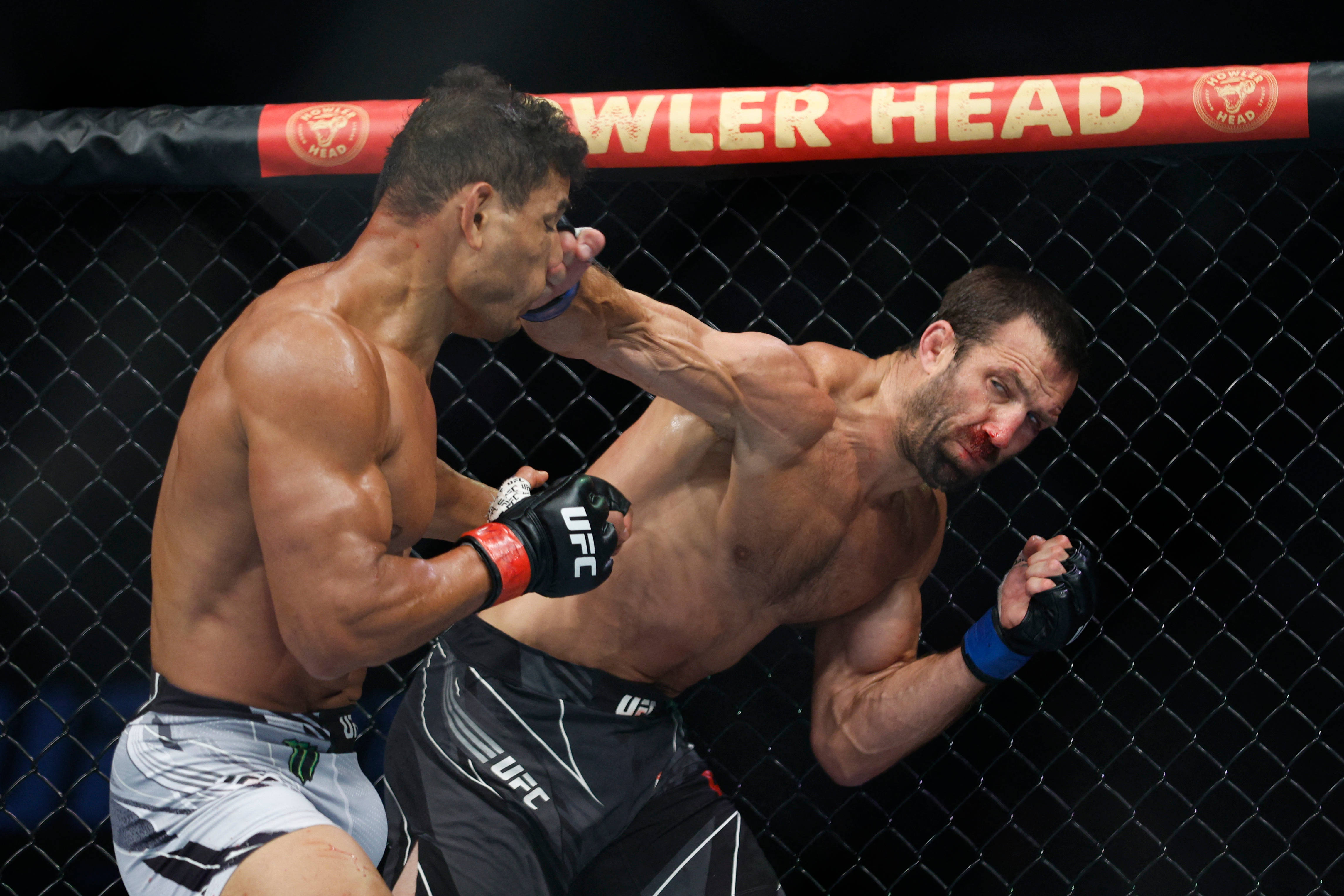UFC 桌布 壁紙 — 兩名肌肉發達的MMA拳手在激烈的鐵籠賽中交鋒，其中一人向對手面部打出強力一拳。