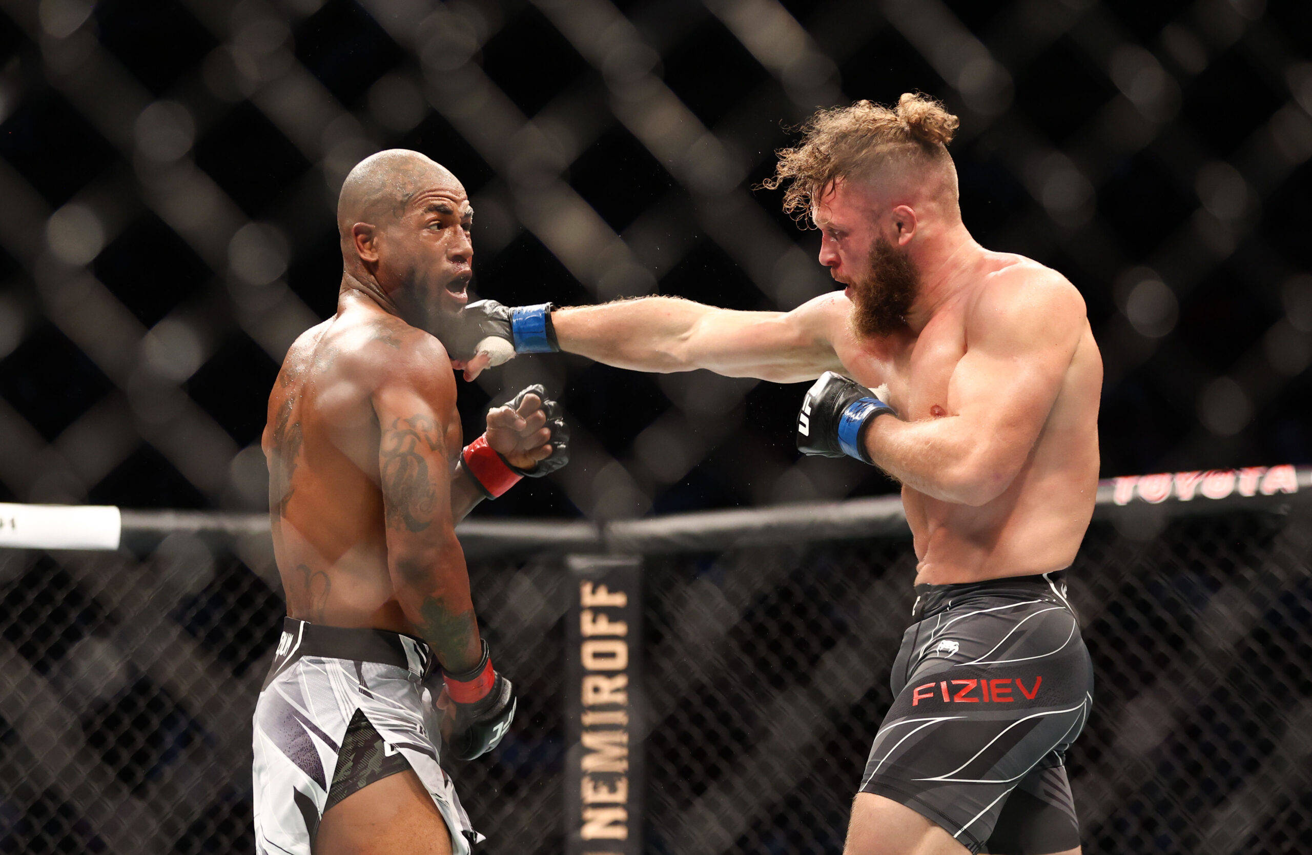 UFC 桌布 壁紙 — 兩名肌肉發達的MMA拳手在激烈的鐵籠賽中交鋒，其中一人打出強力一拳。
