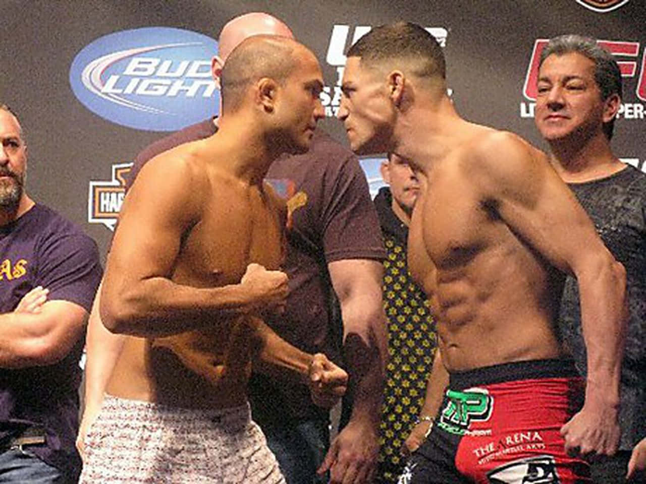 MMA 桌布 壁紙 — 兩名肌肉發達的MMA拳手在稱重儀式上激烈對峙，身後有贊助商標誌。