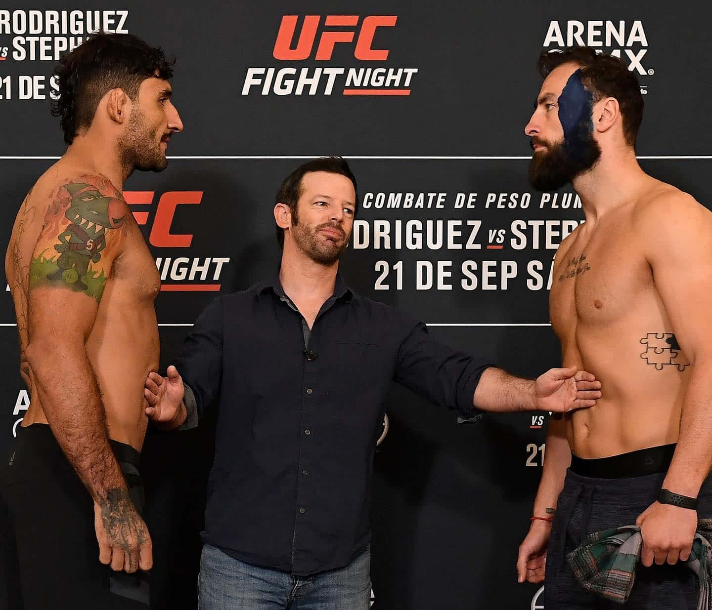 UFC 桌布 壁紙 — 兩名肌肉發達的UFC拳手在品牌背景前對峙，中間有裁判進行稱重。