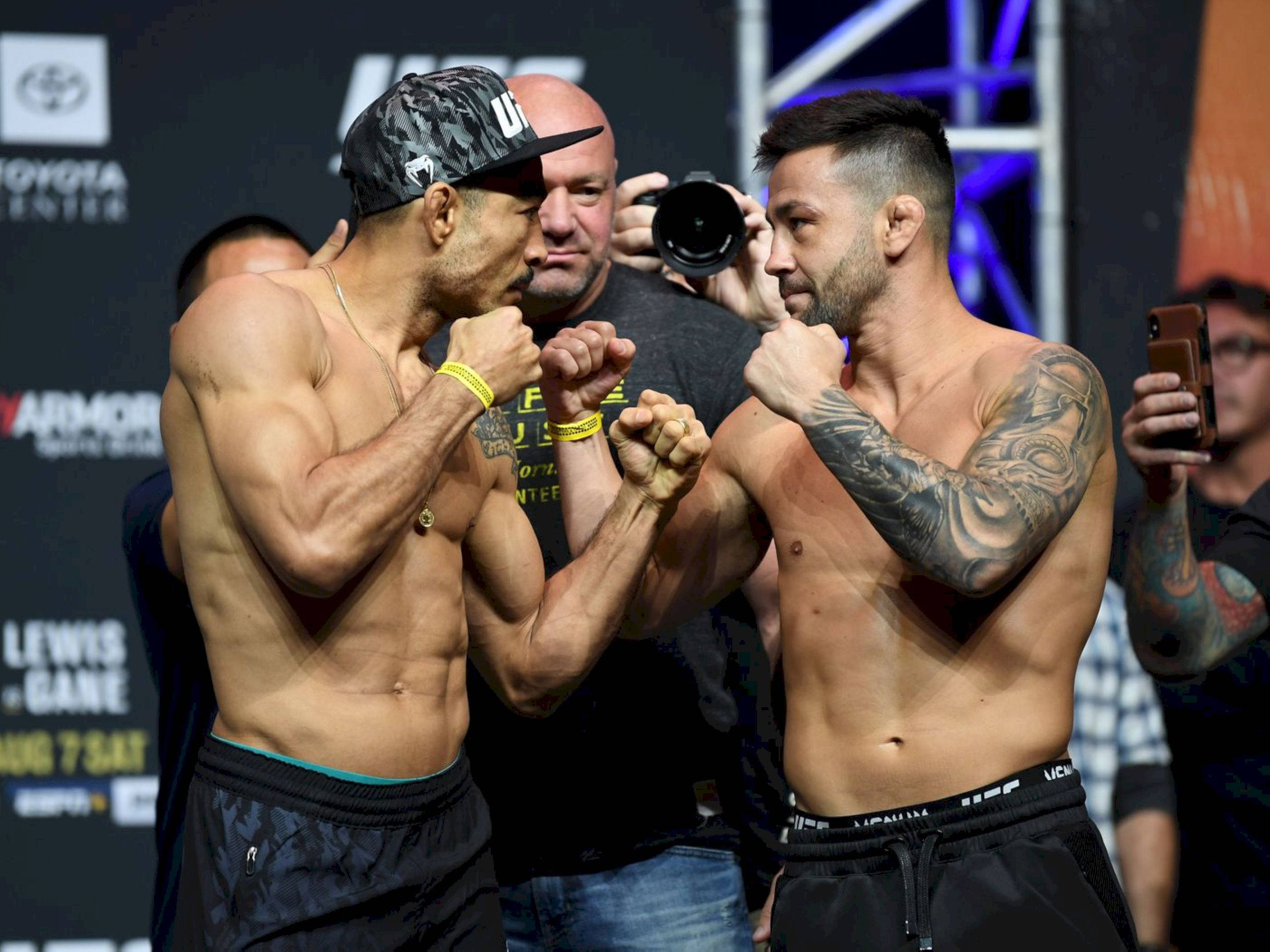 Champion 桌布 壁紙 — 兩名肌肉發達的UFC拳手在明亮的場館燈光下舉起拳頭，進行緊張的賽前對峙。