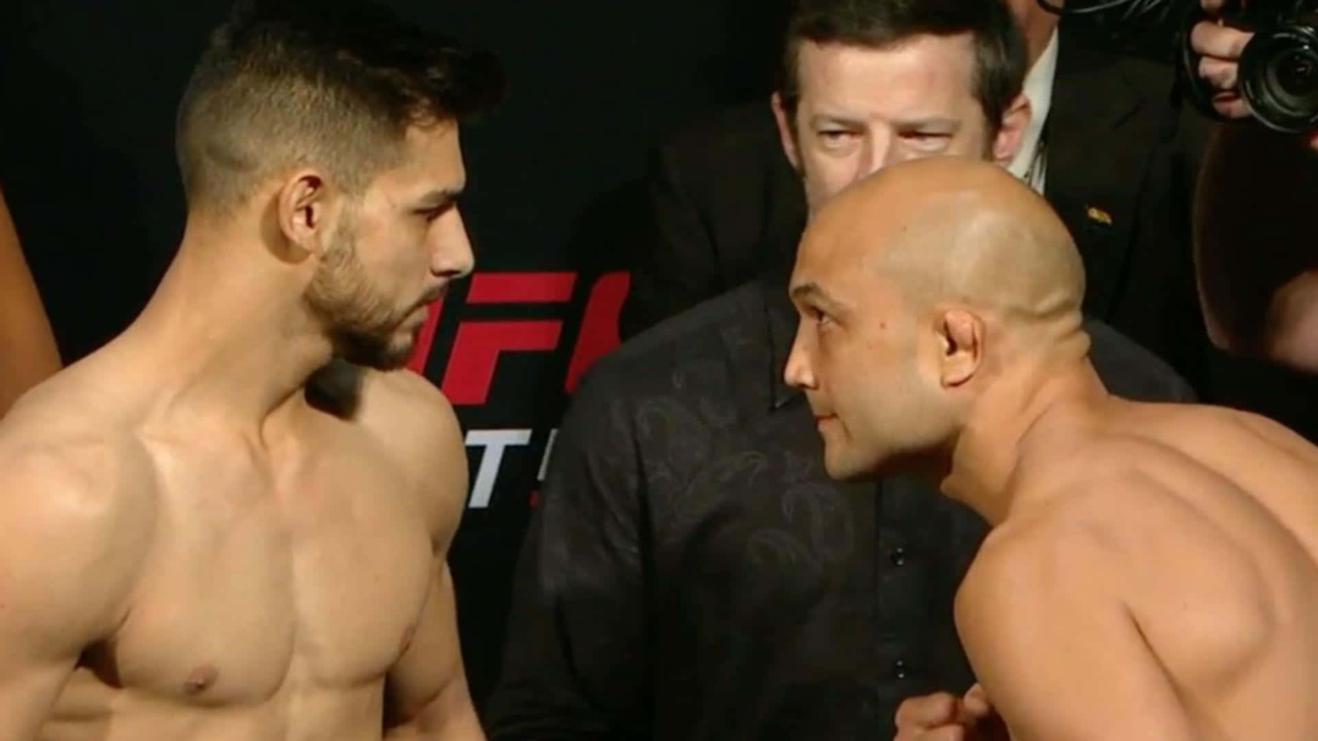 MMA 桌布 壁紙 — 兩名肌肉發達的UFC拳手在明亮的場館燈光下，於緊張的賽前面對面對峙中互相凝視。