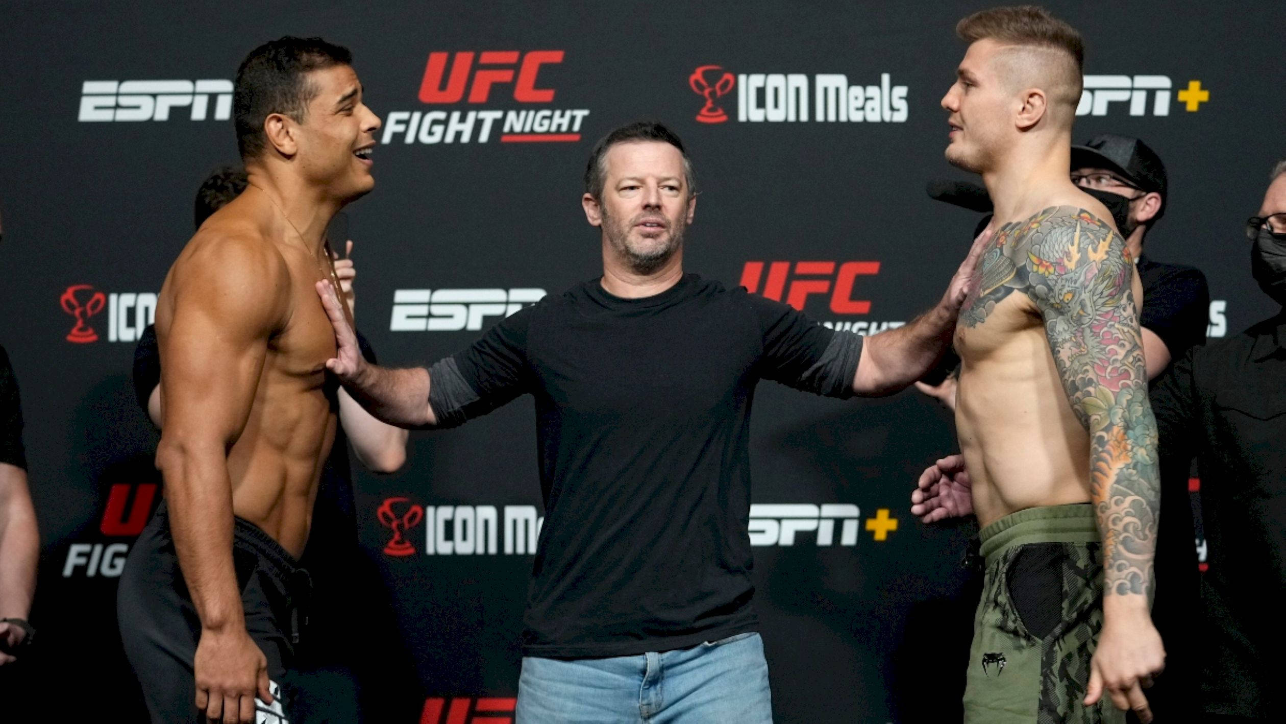 MMA 桌布 壁紙 — 兩名肌肉發達的UFC拳手在稱重時對峙，中間有裁判，背景有品牌標誌。