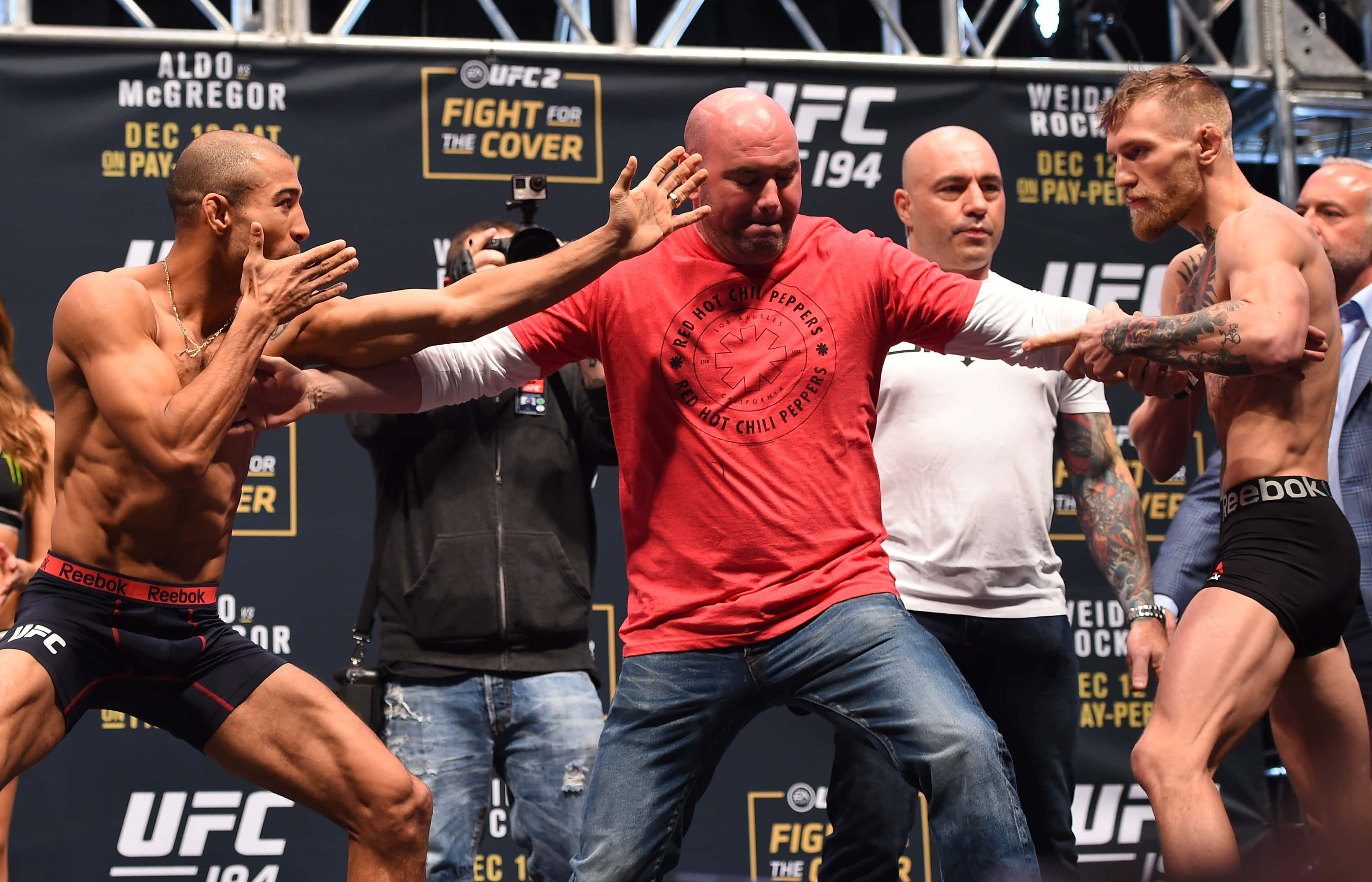 UFC 桌布 壁紙 — 兩名肌肉發達的UFC拳手在稱重時對峙，裁判將他們分開。