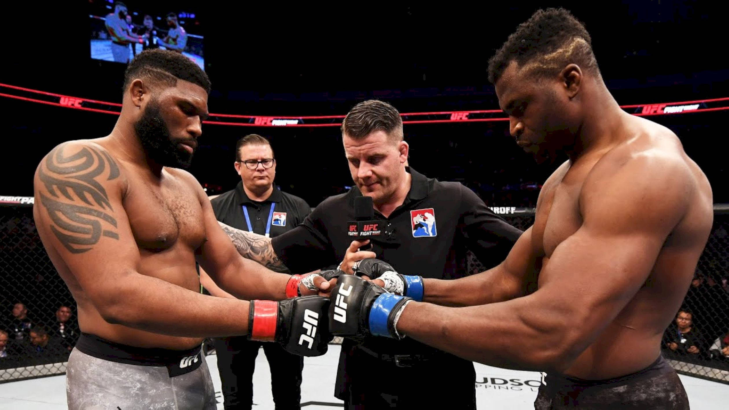 MMA 桌布 壁紙 — 兩名肌肉發達的UFC拳擊手戴著手套，在裁判的注視下，在燈光昏暗的八角籠內鎖手。