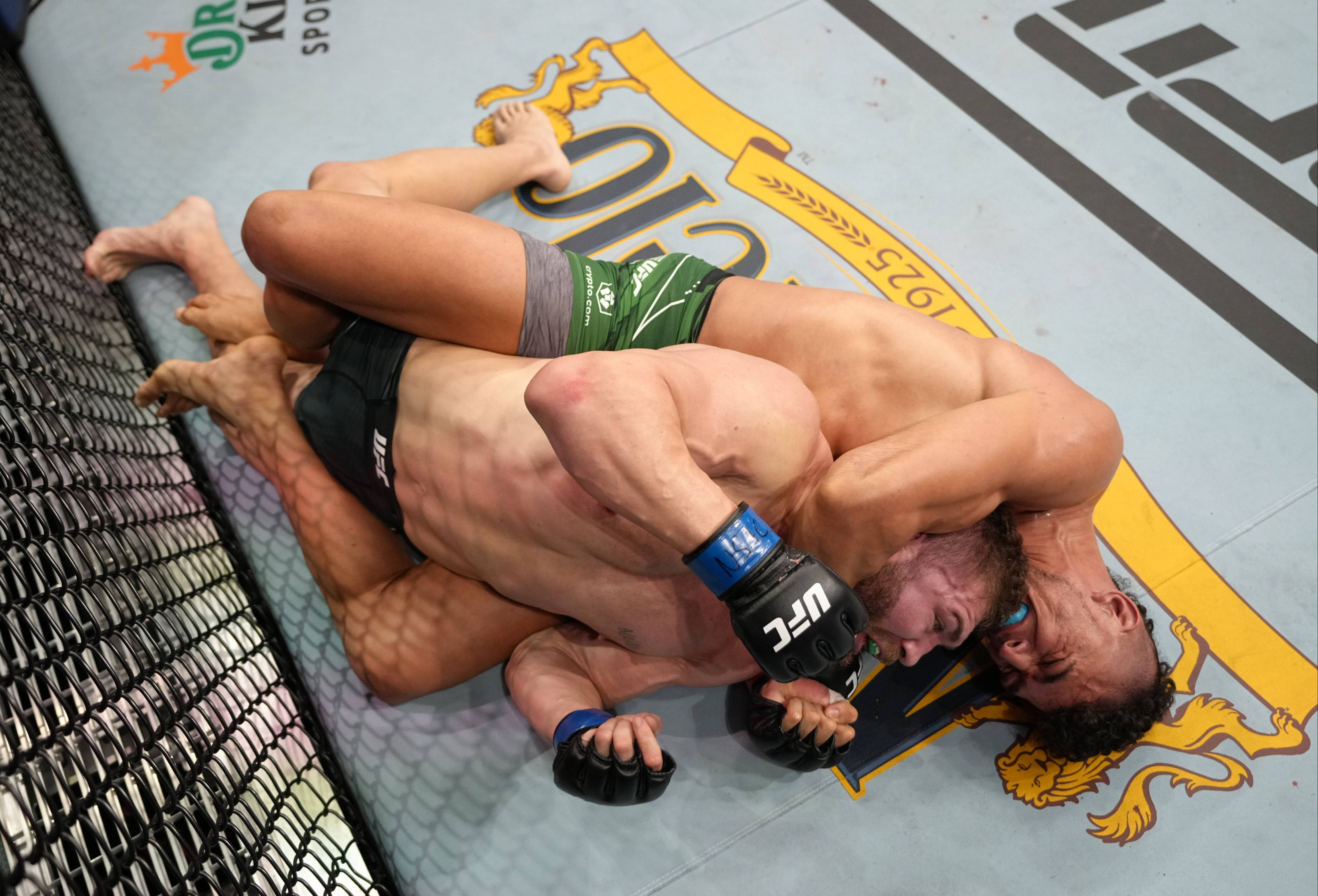 MMA 桌布 壁紙 — 兩名肌肉發達的拳手在UFC八角籠墊上激烈纏鬥，其中一人施展鎖喉技。