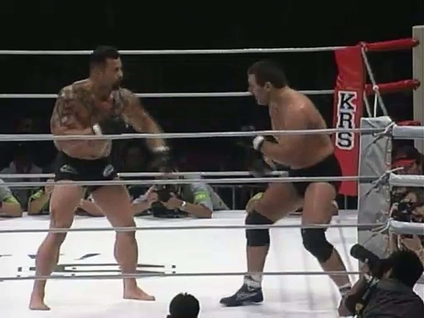UFC 桌布 壁紙 — 兩名肌肉發達的拳手在拳擊台上，在明亮的場館燈光下互相出拳，攝影師捕捉這緊張時刻。