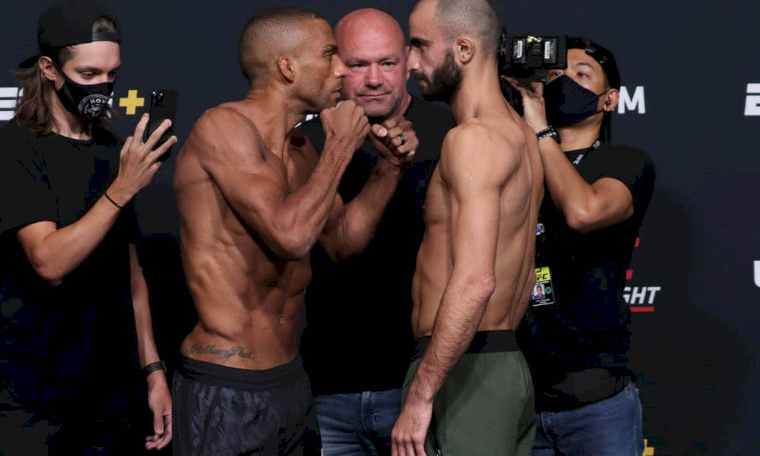 MMA 桌布 壁紙 — 兩名肌肉發達的拳手在明亮的場館燈光下，於賽前緊張地對峙。