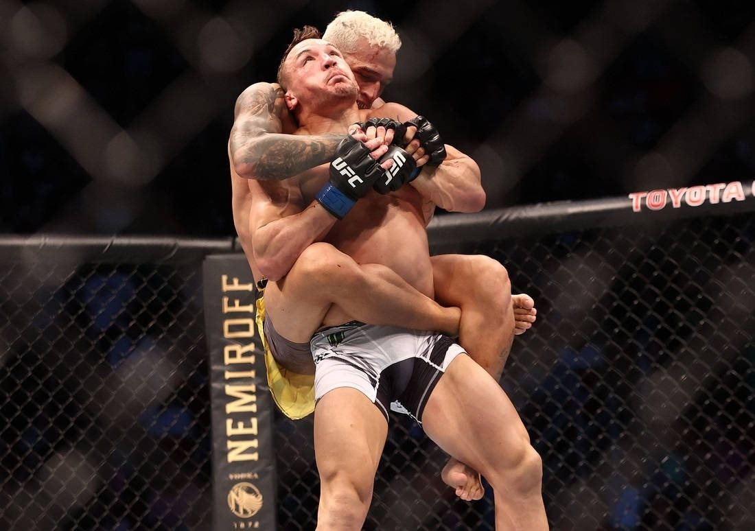 Michael Chandler 桌布 壁紙 — 兩名肌肉發達的拳手在明亮的場館燈光下於UFC八角籠內激烈纏鬥。