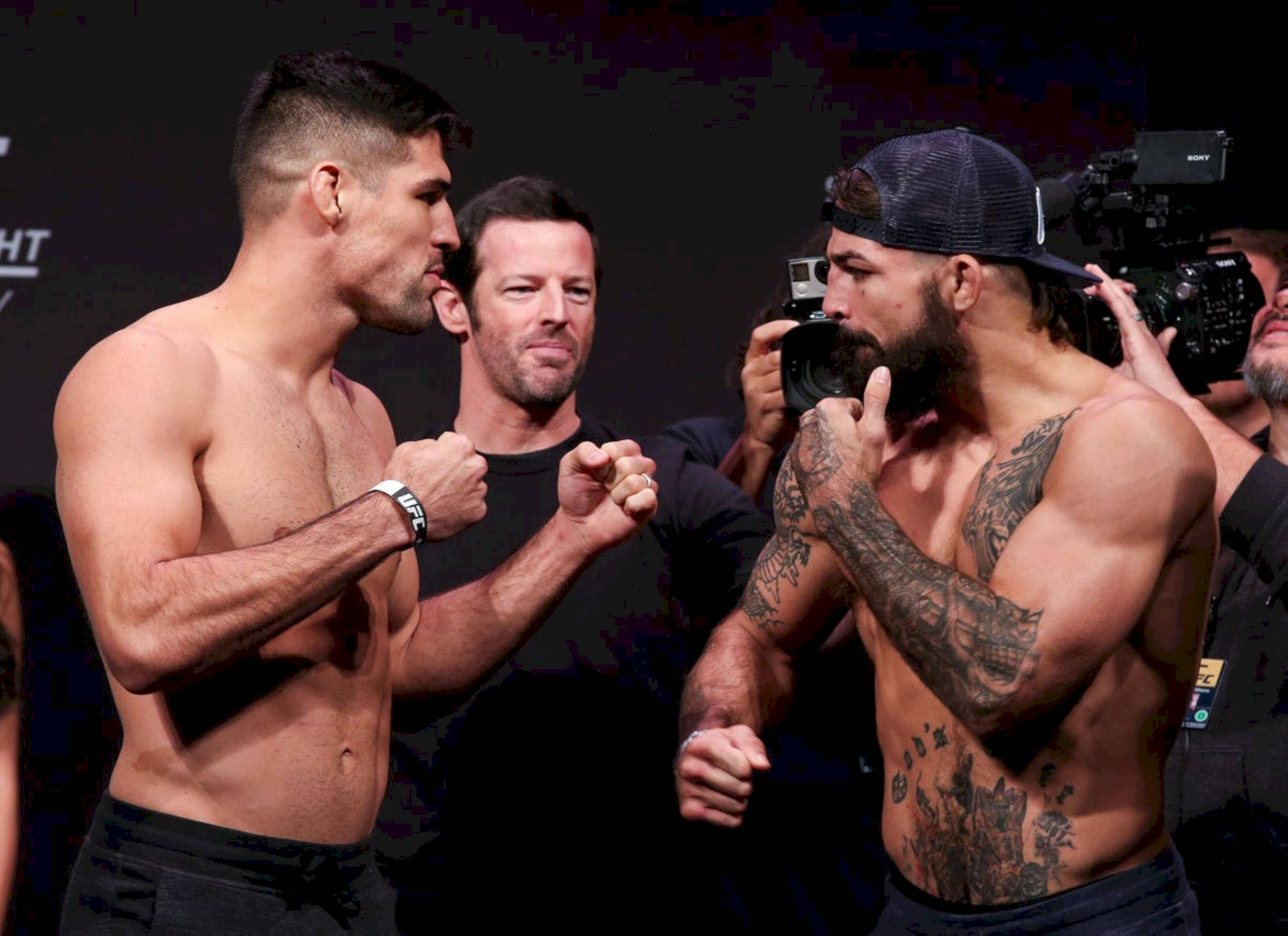 UFC 桌布 壁紙 — 兩名肌肉發達的拳手在明亮的場館燈光下，於賽前緊張地對峙。