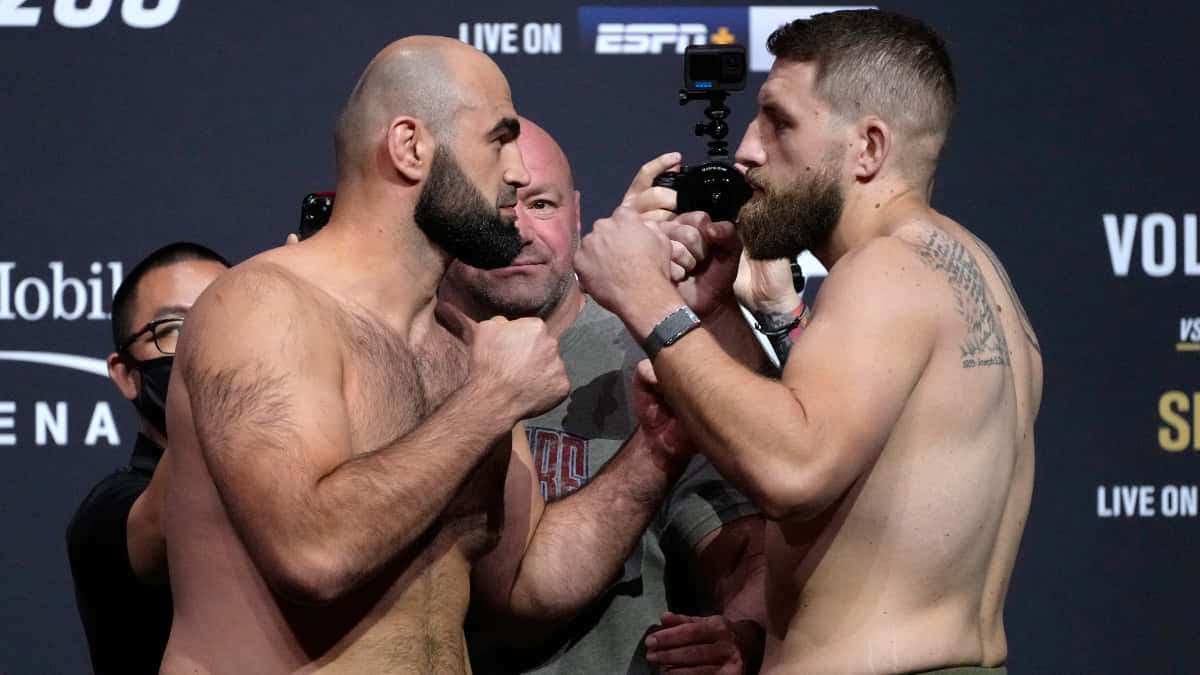 MMA 桌布 壁紙 — 兩名肌肉發達的拳手在稱重儀式上激烈對峙，背景有閃光燈和ESPN品牌標誌。