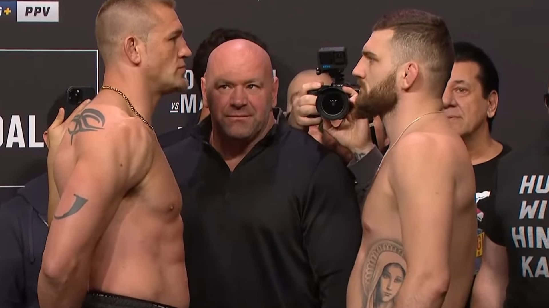 UFC 桌布 壁紙 — 兩名肌肉發達的拳手在稱重時激烈對峙，中間有一位光頭官員，攝影師正在捕捉這一刻。