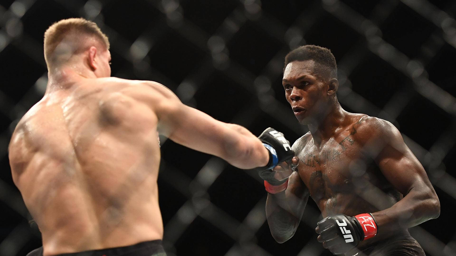MMA 桌布 壁紙 — 兩名肌肉發達的拳手在籠中激戰，其中一人揮拳，汗水在明亮的競技場燈光下閃閃發光。