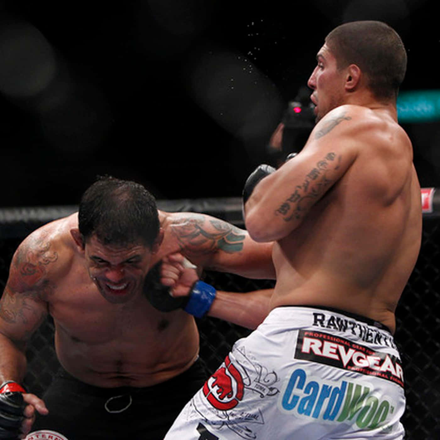 MMA 桌布 壁紙 — 兩名肌肉發達的拳手在鐵籠中激烈交鋒，其中一人揮出強力一拳，汗水飛濺，上演一場高強度的MMA比賽。