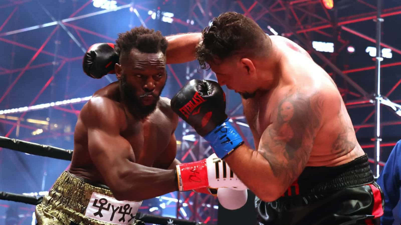 MMA 桌布 壁紙 — 兩名肌肉發達的拳擊手在紅色和藍色舞台燈光下，於燈光明亮的擂台上交鋒。