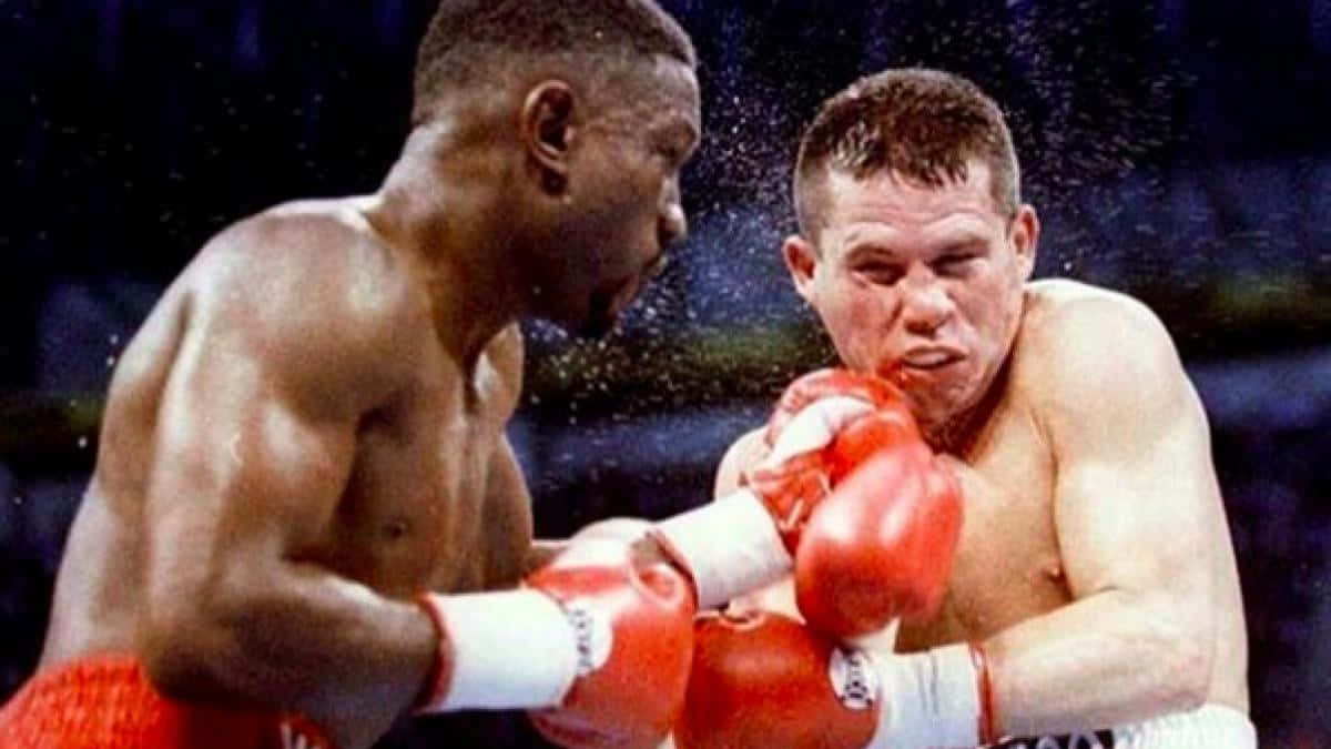 Boxing 桌布 壁紙 — 兩名肌肉發達的拳擊手在雨水飛濺的擂台上交鋒，其中一人向對方臉部猛烈出拳。