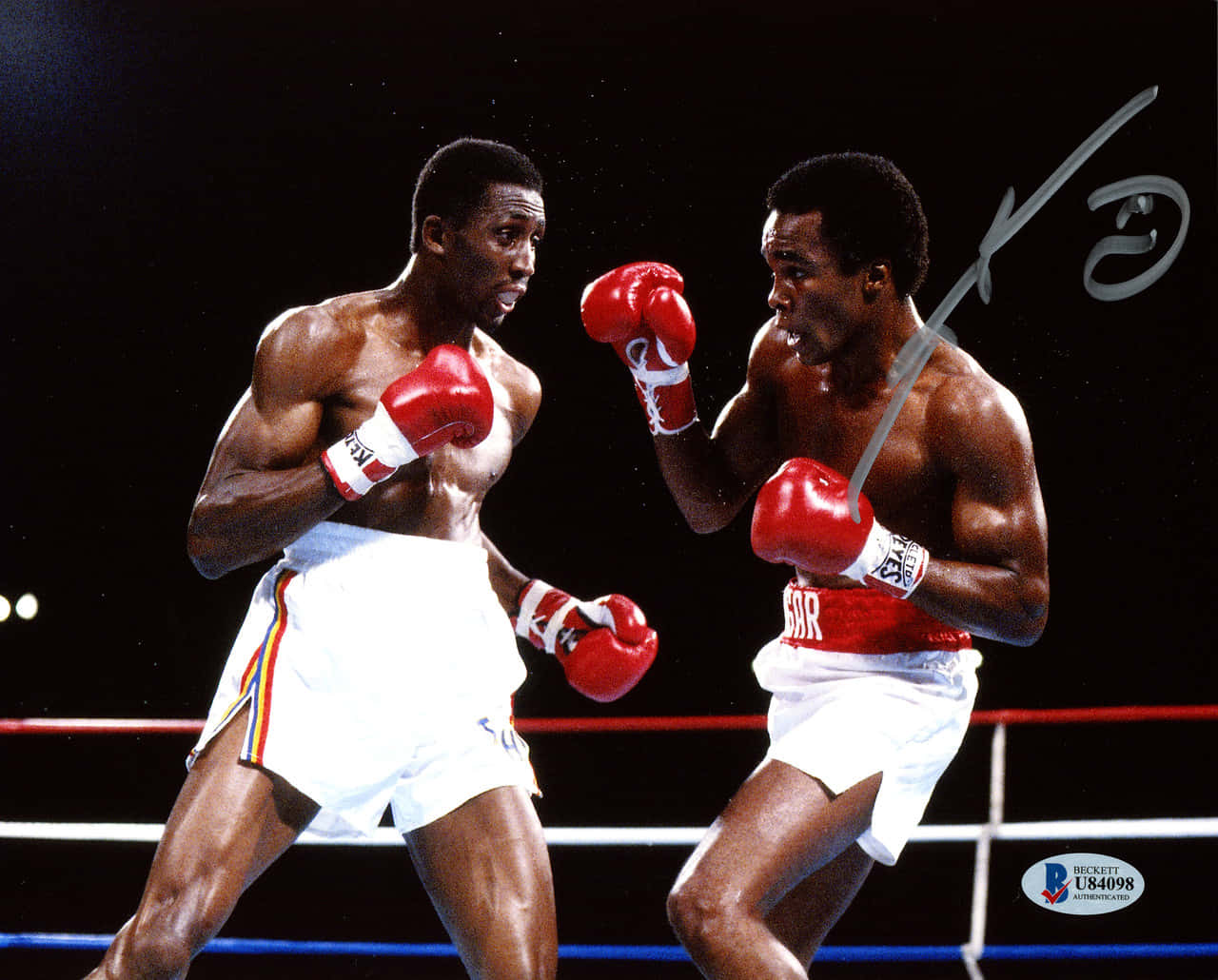 Boxing 桌布 壁紙 — 兩名肌肉發達的拳擊手戴著紅色手套，在黑色背景的明亮擂台燈光下激烈交鋒。