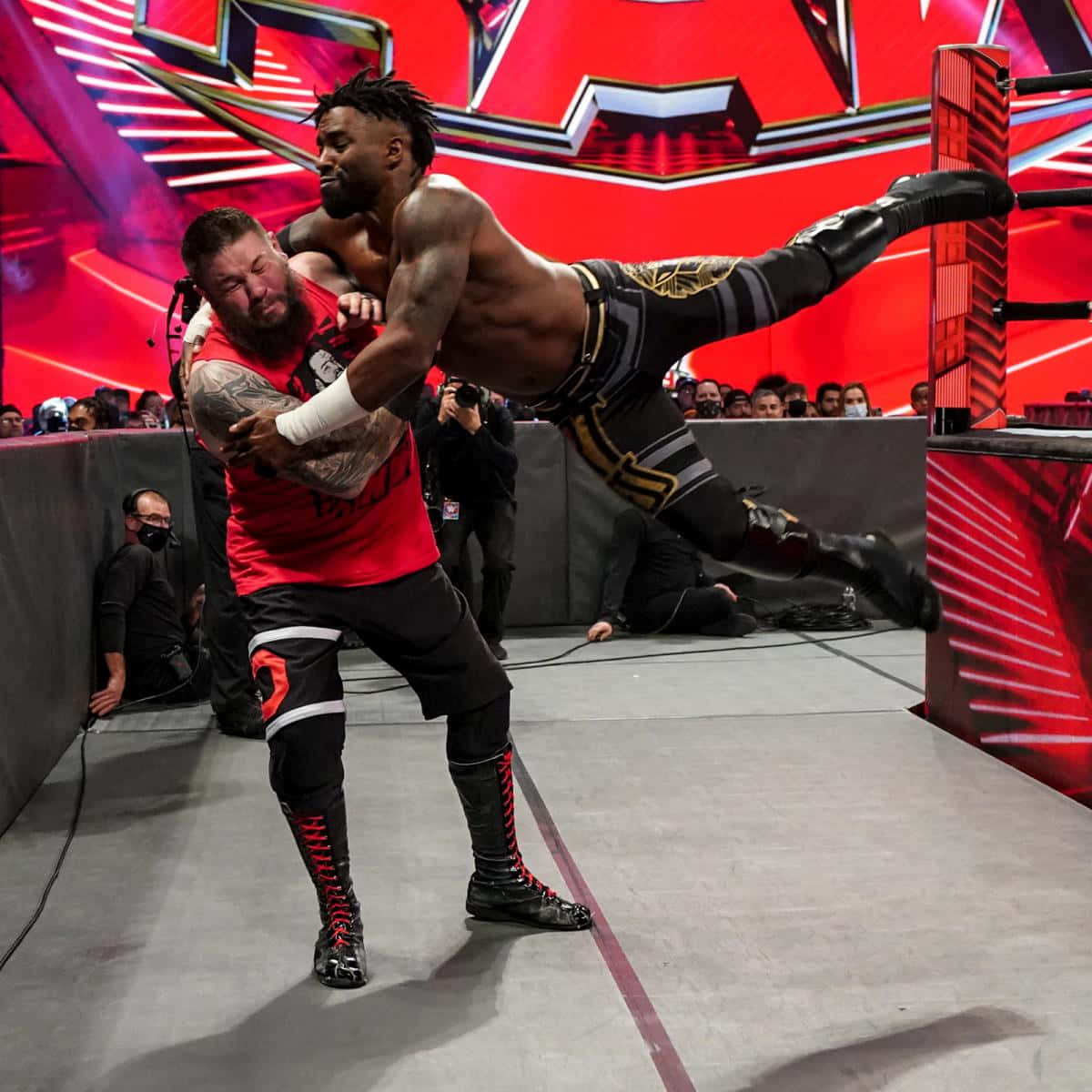 WWE 桌布 壁紙 — 兩名肌肉發達的摔角手在充滿活力的擂台上碰撞，紅色燈光與歡呼的人群交織。