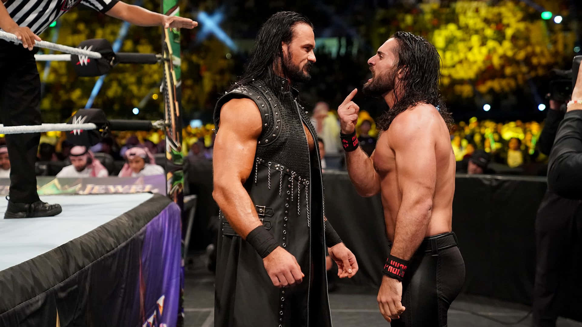 Roman Reigns 桌布 壁紙 — 兩名肌肉發達的摔角手在擂台上對峙，頭頂有裁判，背景是歡呼的人群。
