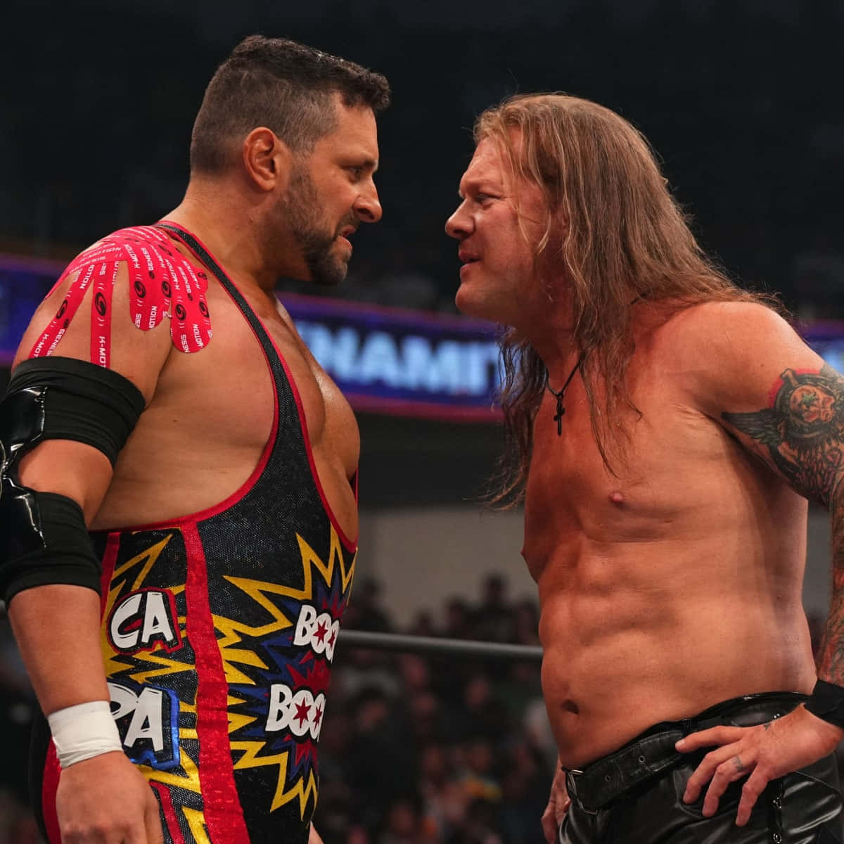 Match 桌布 壁紙 — 兩名肌肉發達的摔角手在擂台上激烈對視，身後有群眾和霓虹燈。