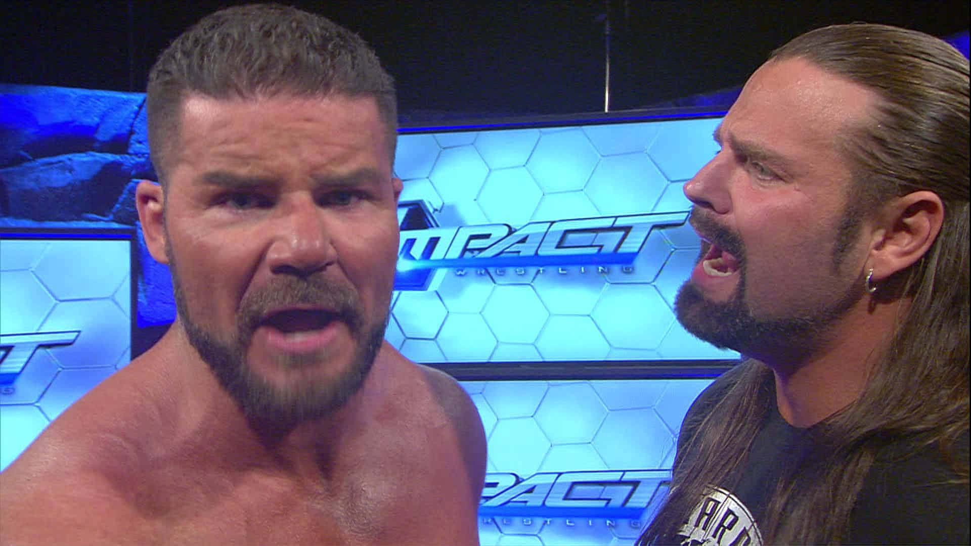 摔角 桌布 壁紙 — 兩名肌肉發達的摔角手在燈光明亮的 Impact Wrestling 擂台上互相怒視。