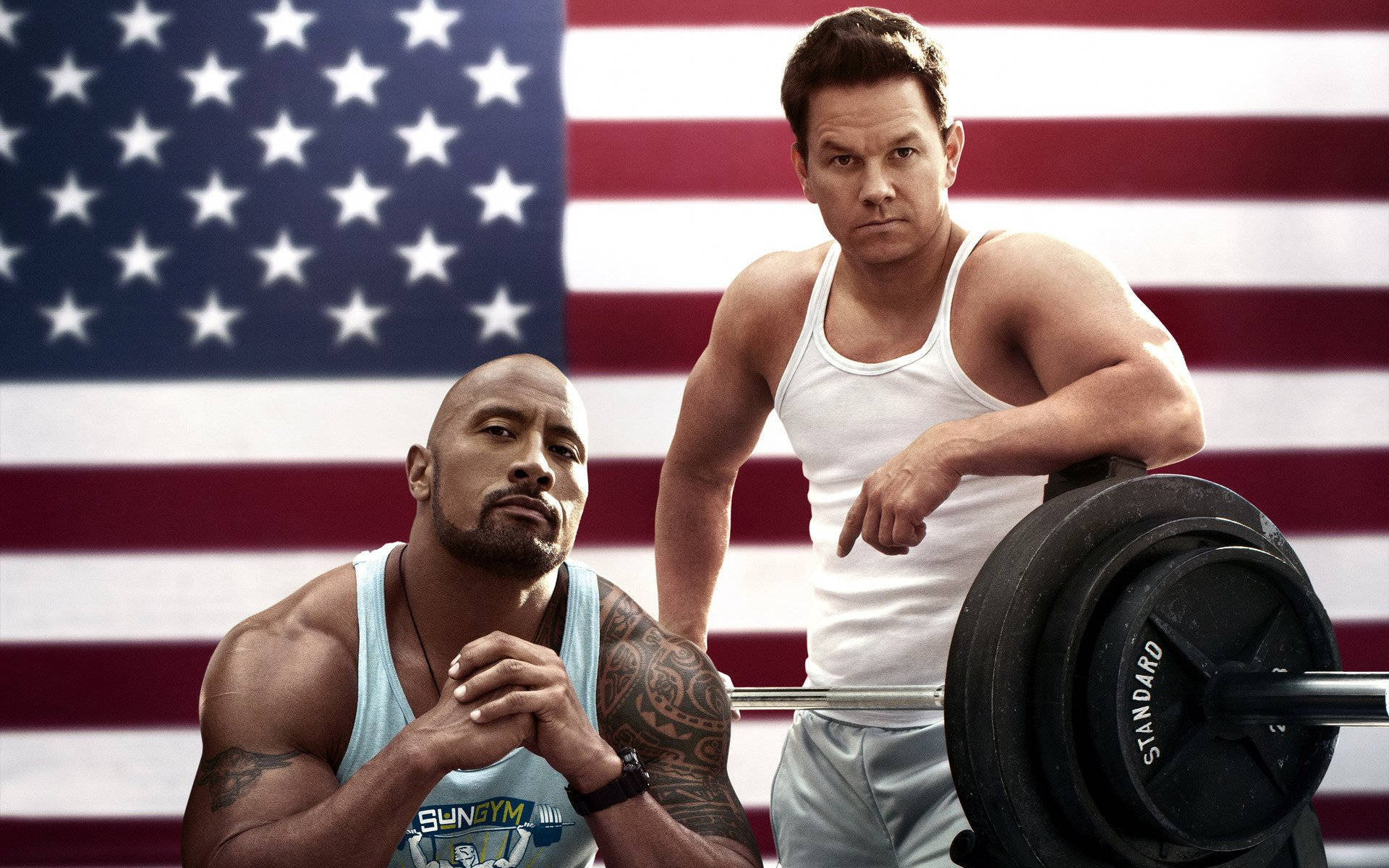 Mark Wahlberg 桌布 壁紙 — 兩名肌肉發達的男子穿著健身背心，在大型美國國旗背景下舉著槓鈴擺姿勢。