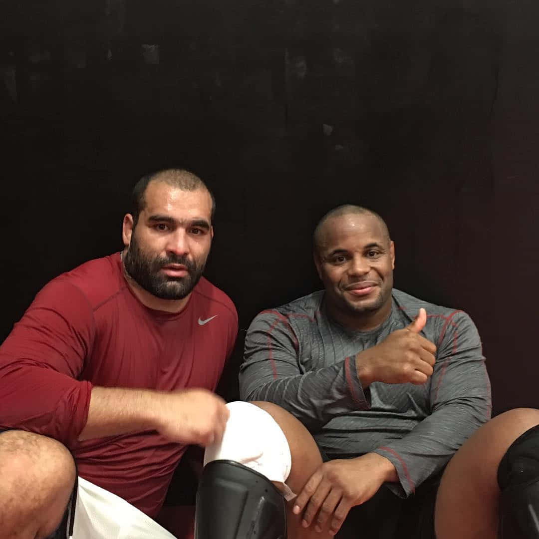 UFC 桌布 壁紙 — 兩名肌肉發達的男子穿著運動服在黑暗背景下自信地擺姿勢，其中一人豎起大拇指。