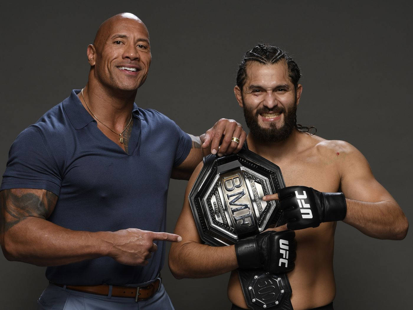 UFC 桌布 壁紙 — 兩名肌肉發達的男子自信地擺姿勢，其中一人手持UFC冠軍腰帶，背景為深色攝影棚。
