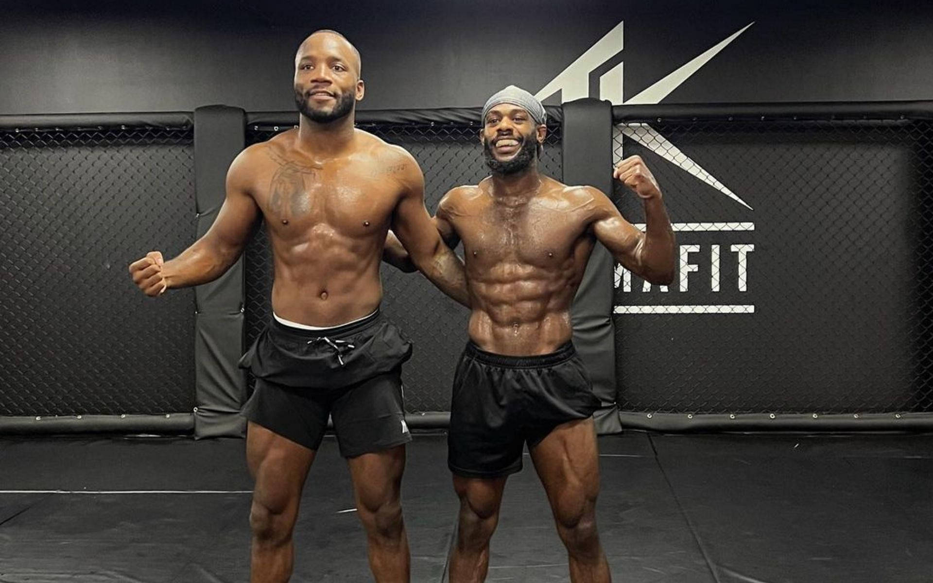 MMA 桌布 壁紙 — 兩名肌肉線條分明的男士自信地在黑色MMA籠內擺姿勢，牆上有'MMAFIT'品牌標誌。