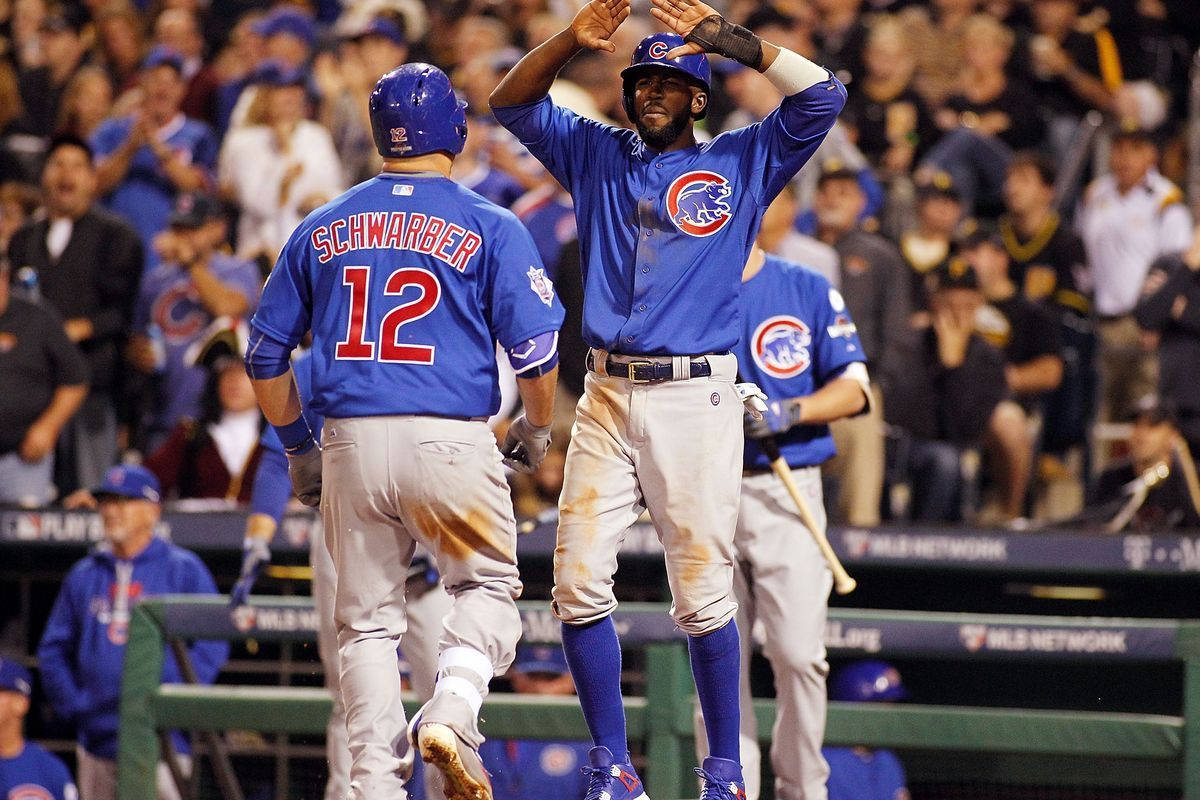 Chicago Cubs 桌布 壁紙 — 兩名芝加哥小熊隊棒球選手在球場燈光下與背景中歡呼的球迷擊掌慶祝一次比賽。