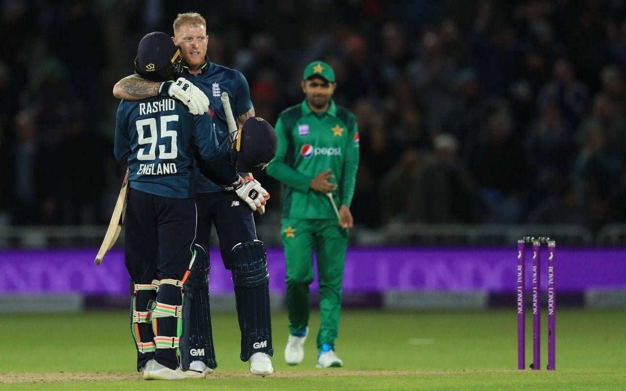 Ben Stokes 桌布 壁紙 — 兩名英格蘭板球運動員在泛光燈照亮的球場上熱情擁抱，背景中一名巴基斯坦球員走開。