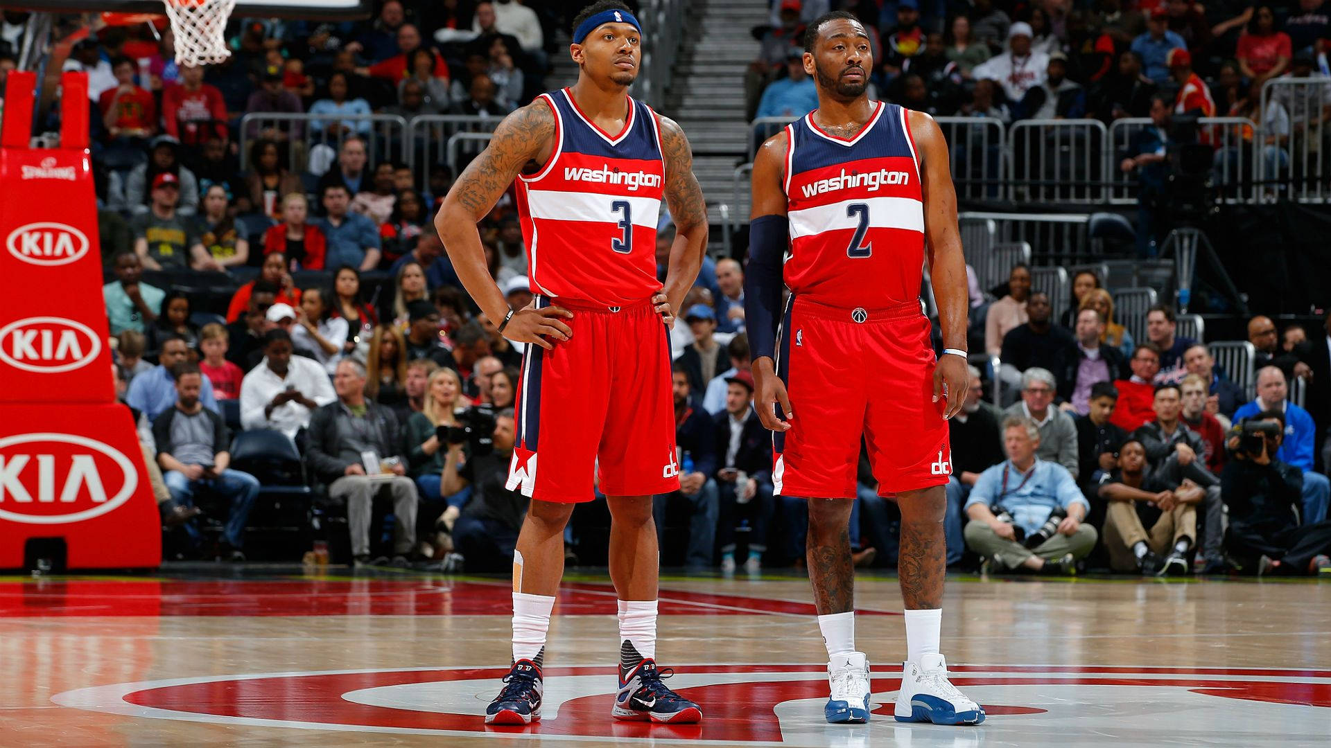 Bradley Beal 桌布 壁紙 — 兩名華盛頓巫師籃球球員在比賽中站在球場上，背景有觀眾。