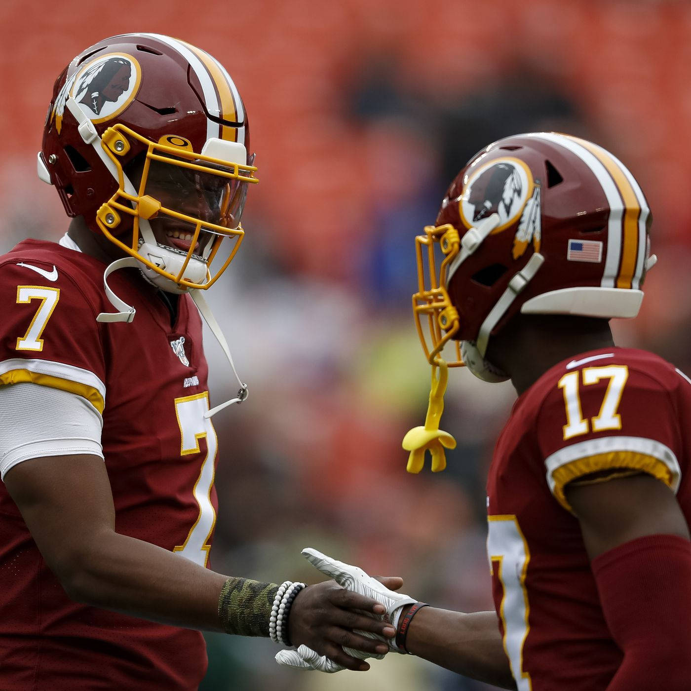 Football Players 桌布 壁紙 — 兩名華盛頓美式足球隊球員身穿栗色和金色裝備在比賽期間於場上握手。