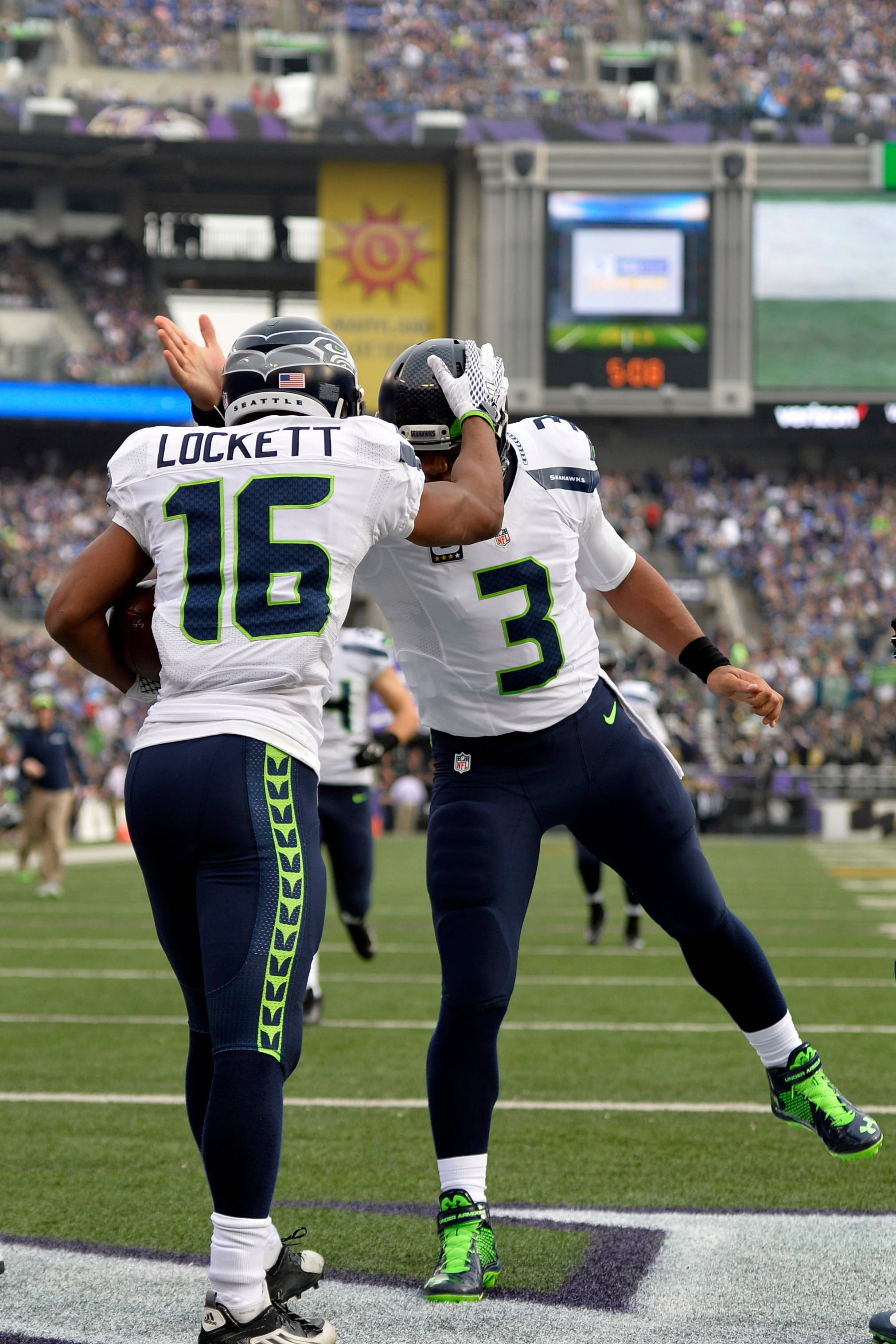 Seattle Seahawks 桌布 壁紙 — 兩名西雅圖海鷹隊美式足球員在球場上慶祝，其中一人在比賽中與另一人擊掌。