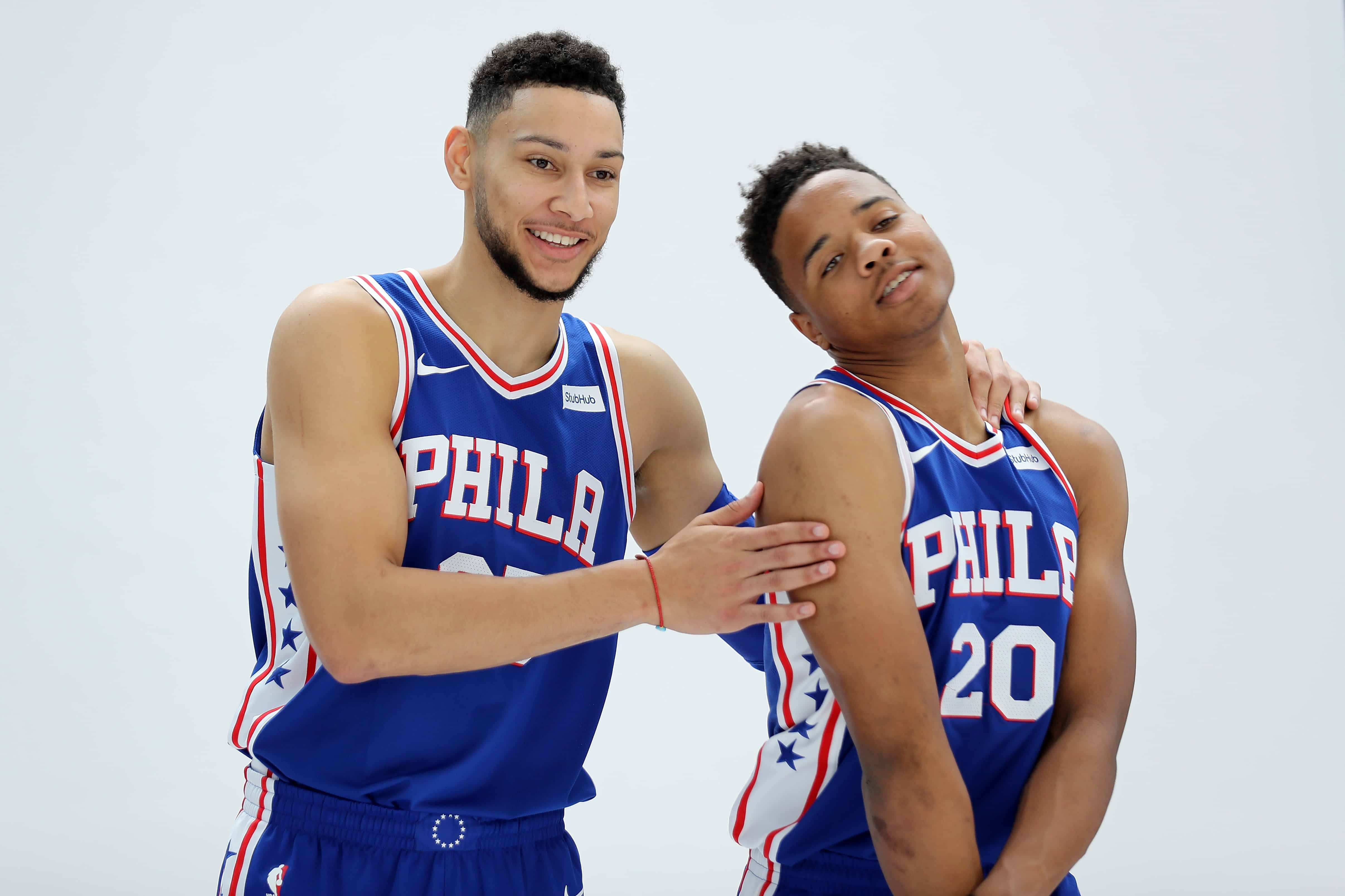 Ben Simmons 桌布 壁紙 — 兩名費城76人籃球運動員身穿藍色星星圖案球衣，微笑著在純白背景前緊密擺姿勢。