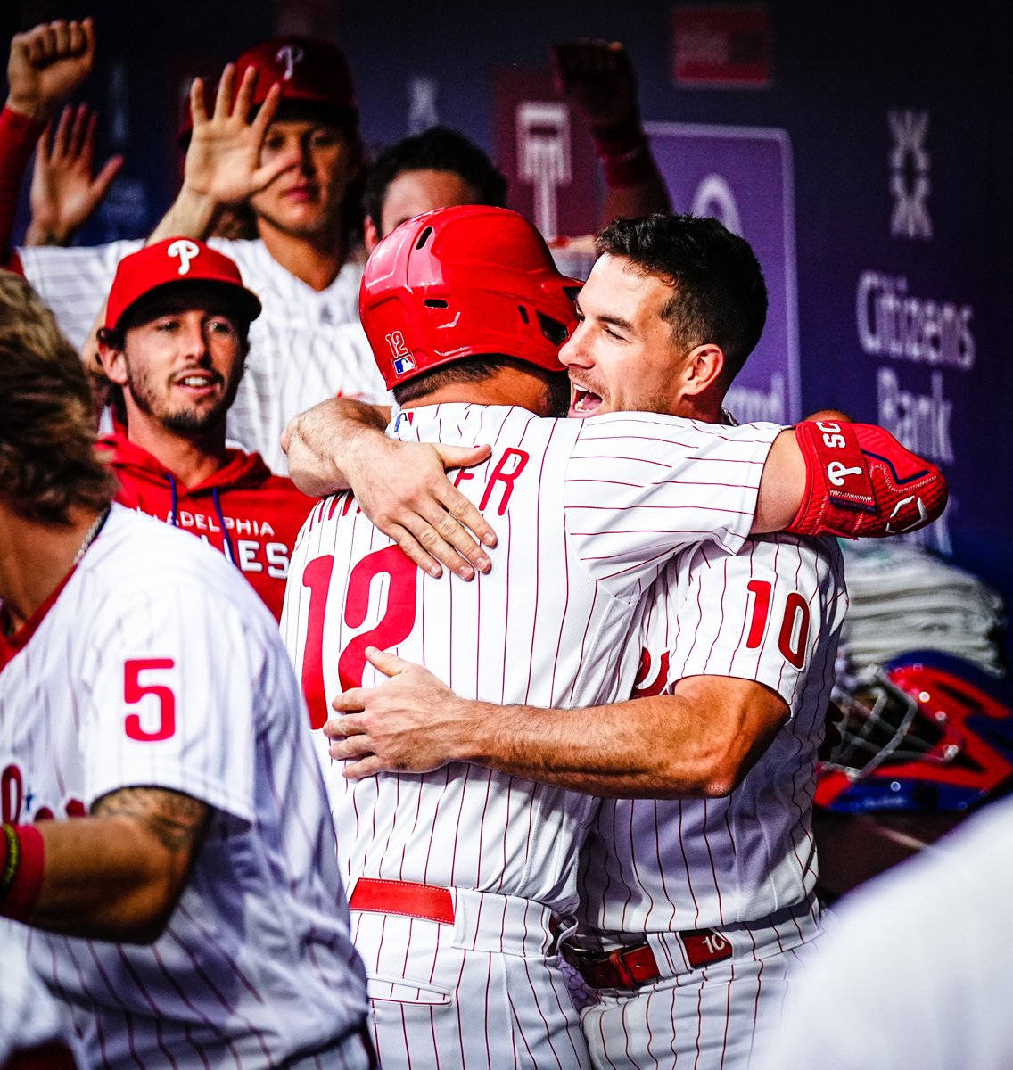 Phillies 桌布 壁紙 — 兩名費城費城人棒球選手身穿細條紋球衣在球員休息區熱情擁抱，隊友在他們身後歡呼。