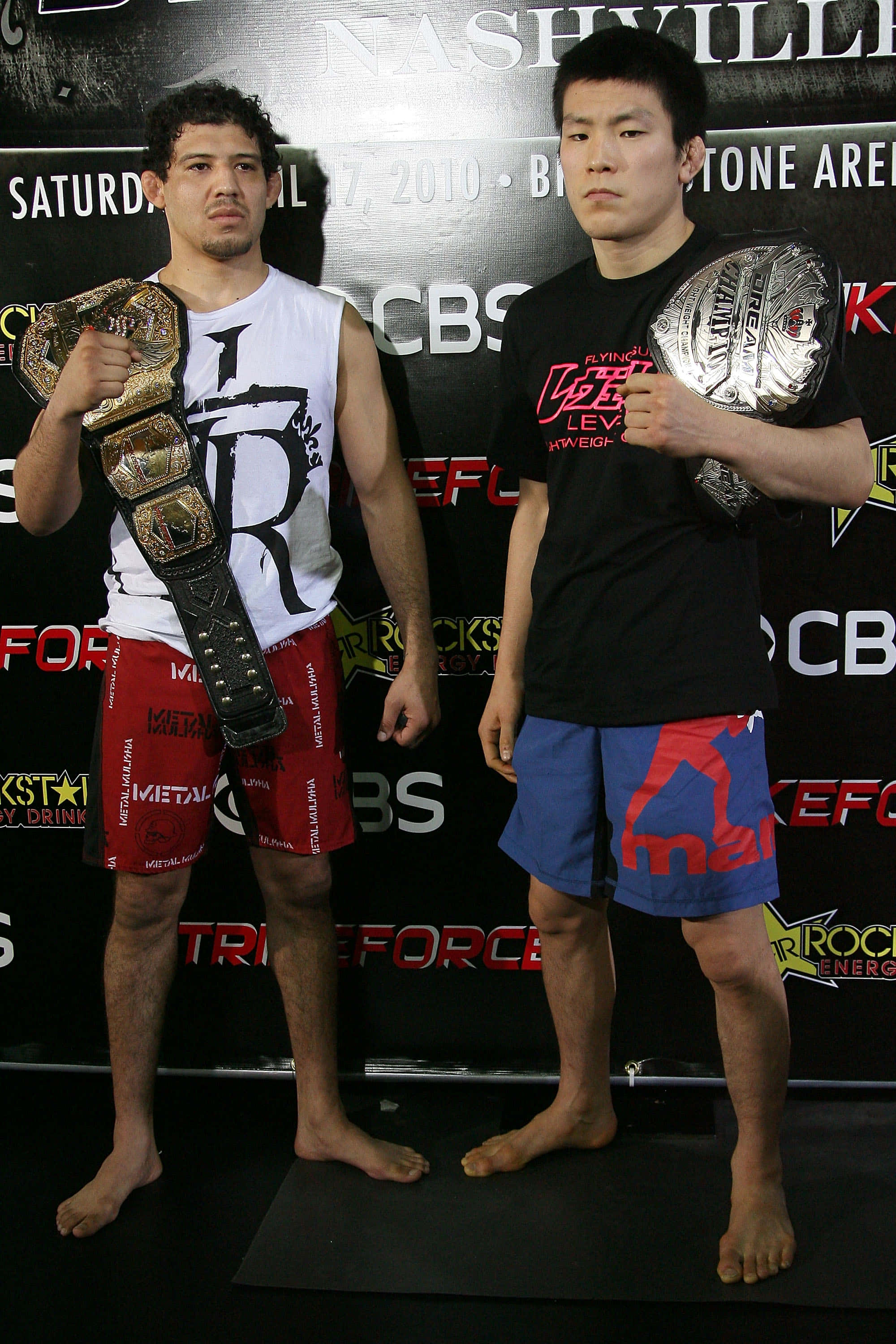 MMA 桌布 壁紙 — 兩名赤腳MMA拳手自信地站在品牌活動背景前，手持冠軍腰帶。